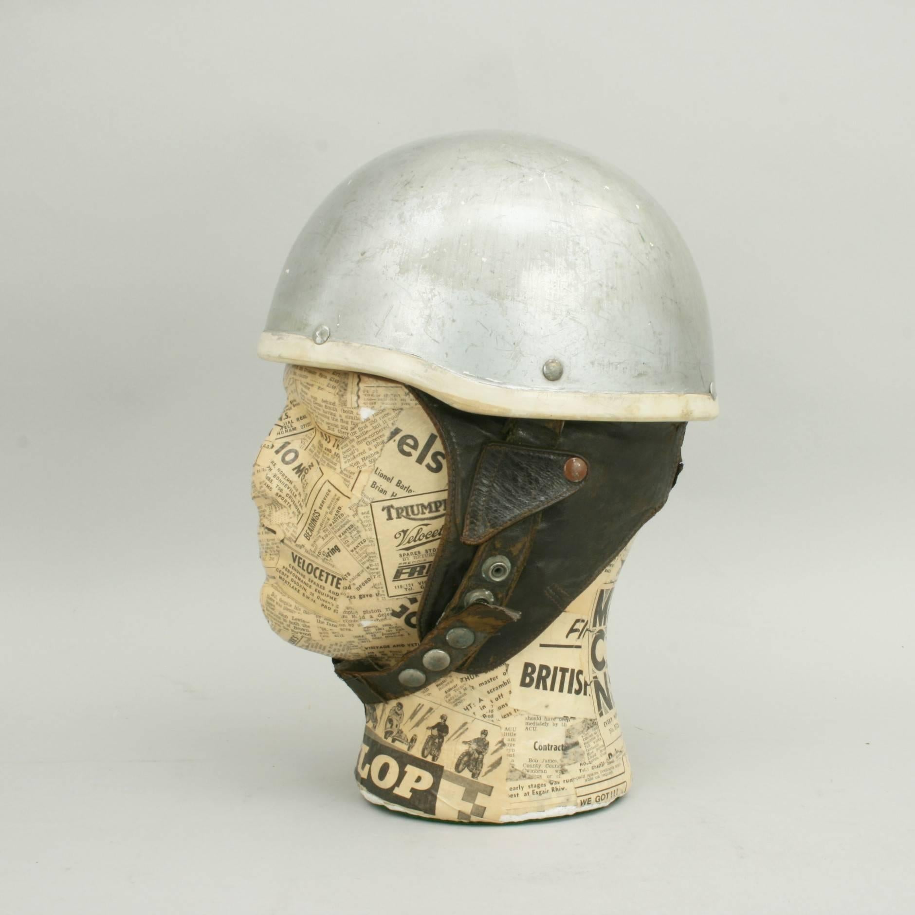 A good pudding basin motorcycle helmet made in England by Cromwell. The outer shell is painted silver with a material interior. Strong leather neck and earflaps are also fitted as is a chin strap. Inside the helmet is a Cromwell trade label. A good
