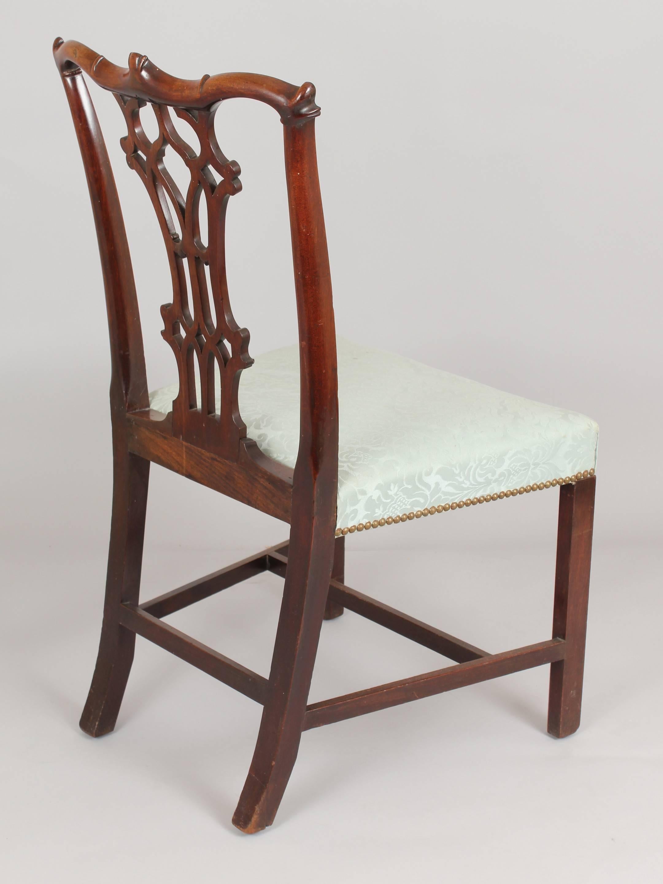 A fine pair of George III period mahogany side-chairs in the Chippendale manner with carved Gothic style splats and shaped cresting-rails; the stuff-over seats covered in green damask and on chamfered legs with stretchers.