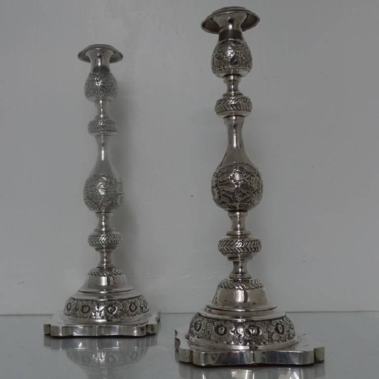 A very elegant pair of large silver sabbath candlesticks with beautiful floral embossing for decoration. The sticks have shaped square bases which have been filled. The nozzles are detachable and have stylish engraving for highlights.