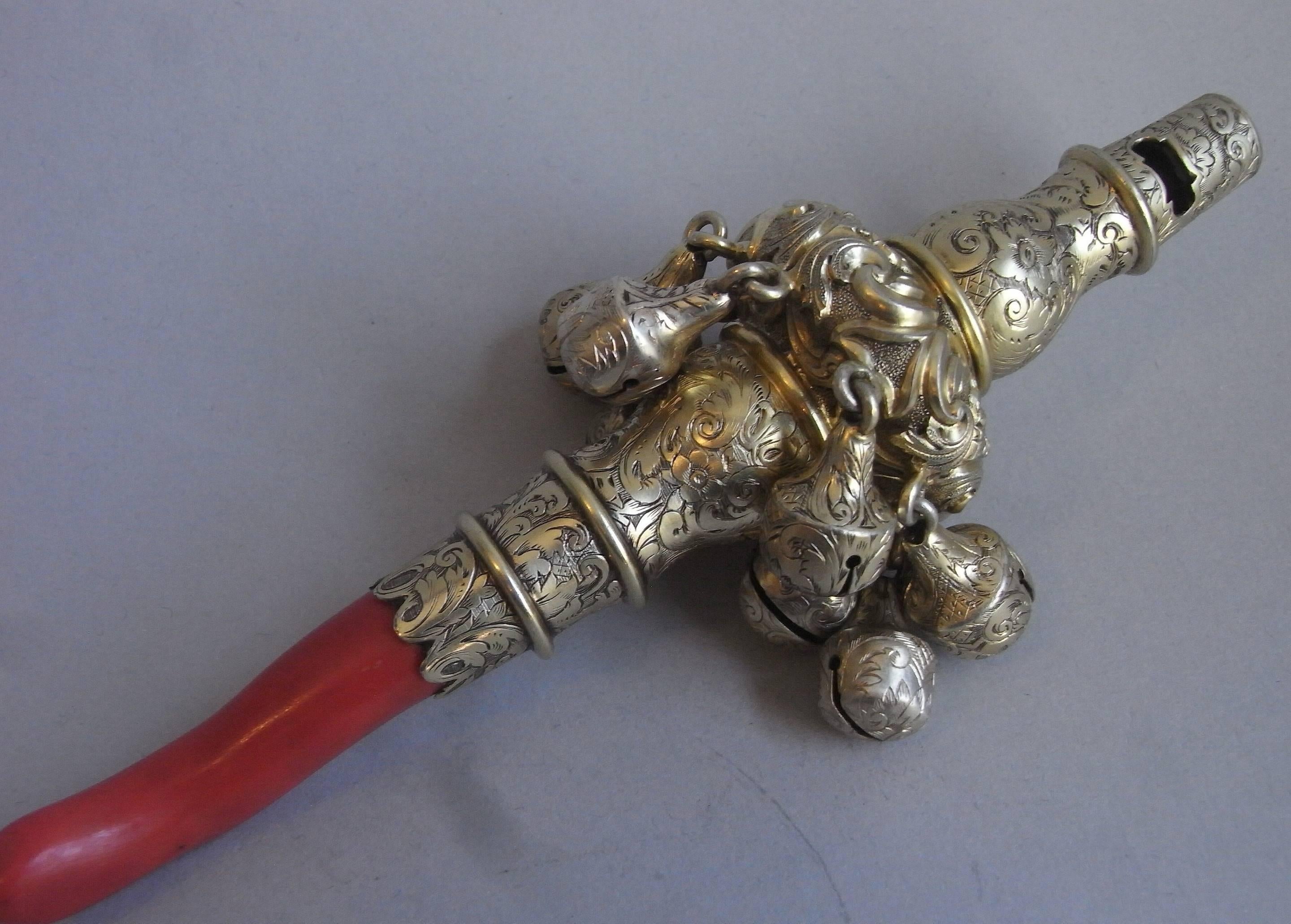 The Rattle is silver gilt and the main shaft has a shaped baluster form, displaying five plain circular raised girdles along its length. The central section is chased with Rococo scrolls and flower heads and the rest of the shaft is beautifully