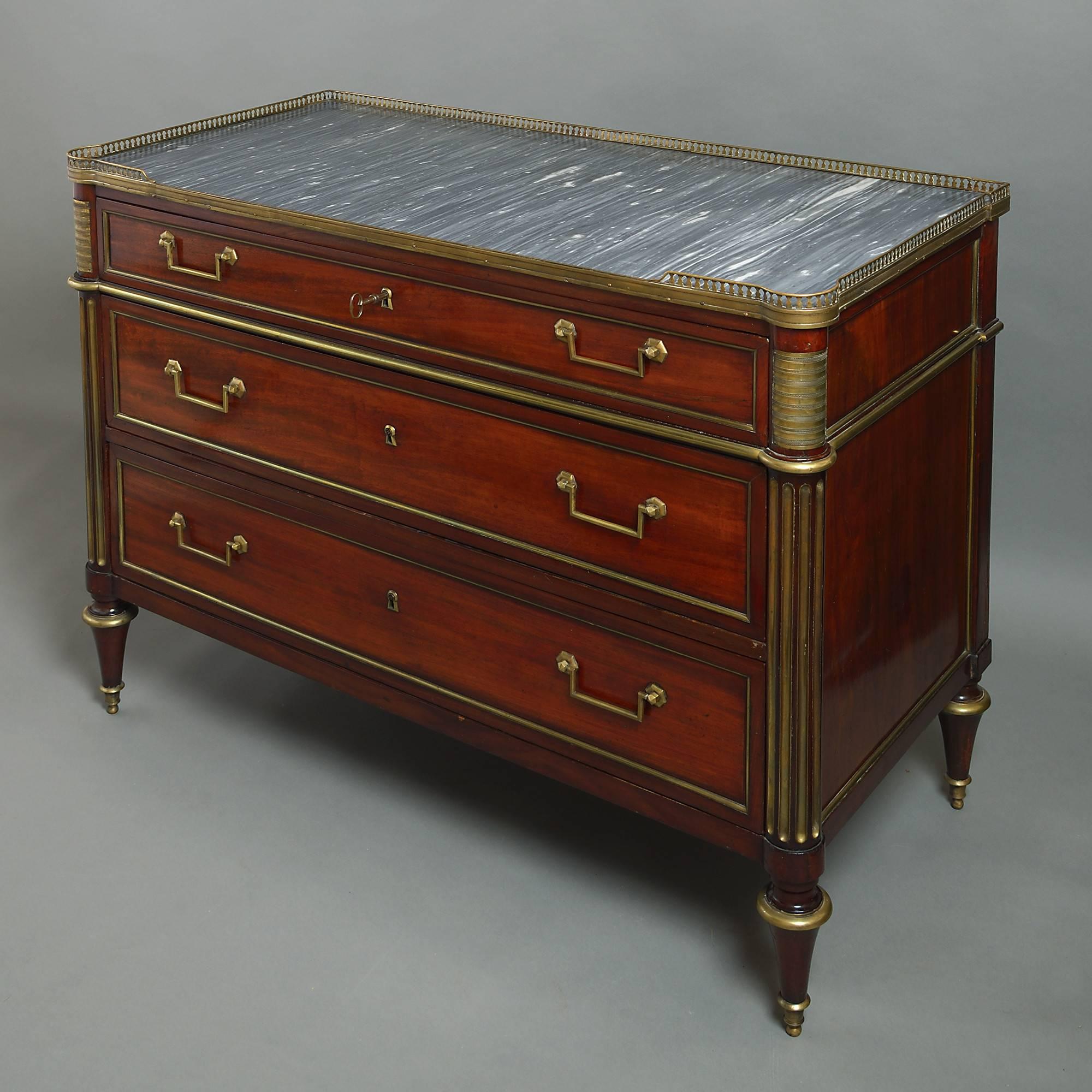 A late 18th century Louis XVI Period mahogany commode, the inset grey marble top with pierced brass gallery above three long brass-mounted drawers with rectangular handles and lock escutcheons, the sides of column-form with washboard mounts and