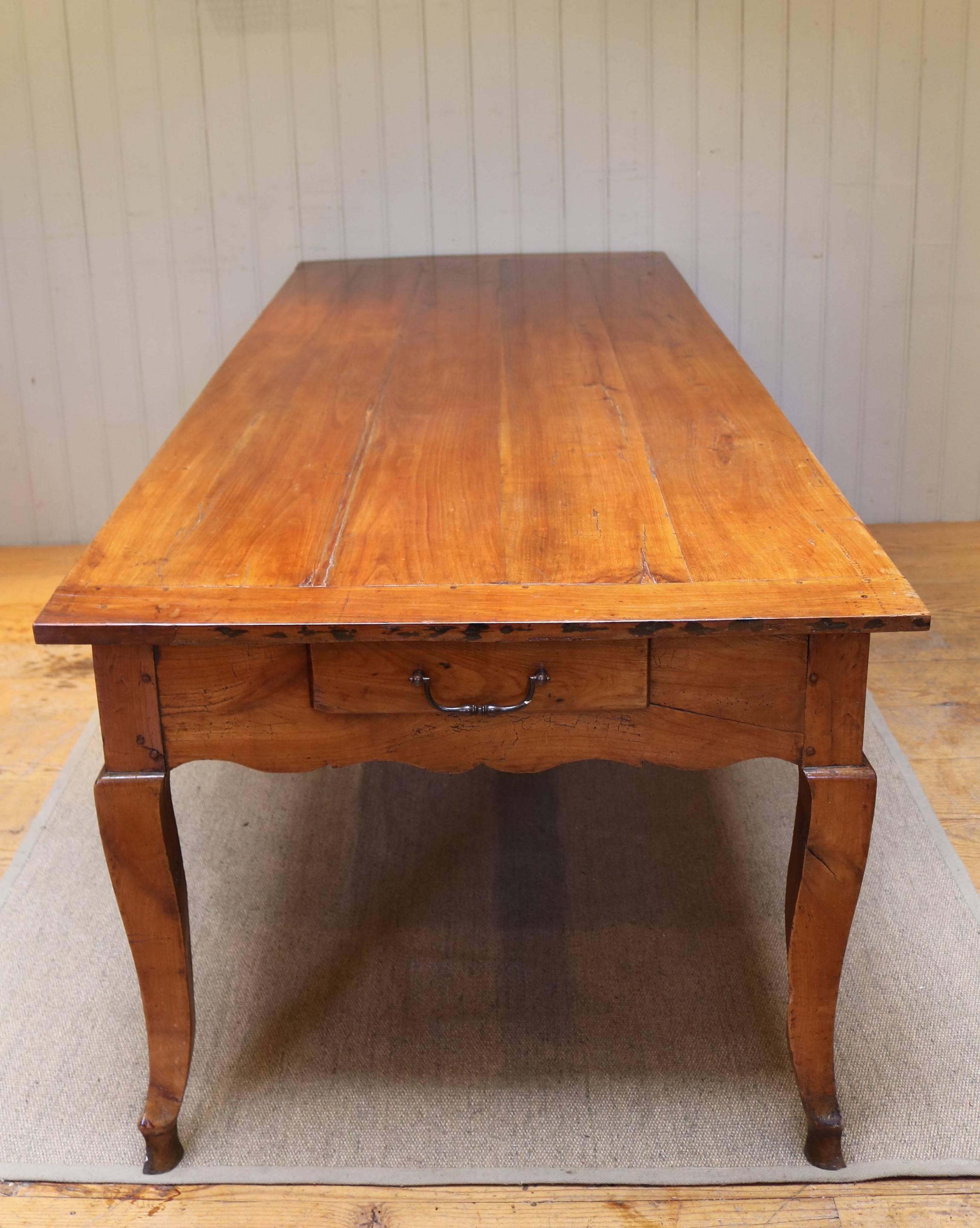 Substantial cherrywood farmhouse table having a three plank top with cleated ends, there is a cutlery drawer to one end and a pull-out chopping slide to the other, raised on shaped legs with a fluted apron to the underside.The height to the fluted