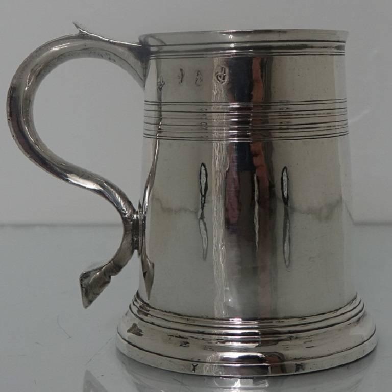 A delightful Britannia silver half pint mug, cylindrical in design with elegant upper bands of reeding for highlights. The foot is flared and the handle is scroll formed and crowned with shaped sheet silver thumb piece.