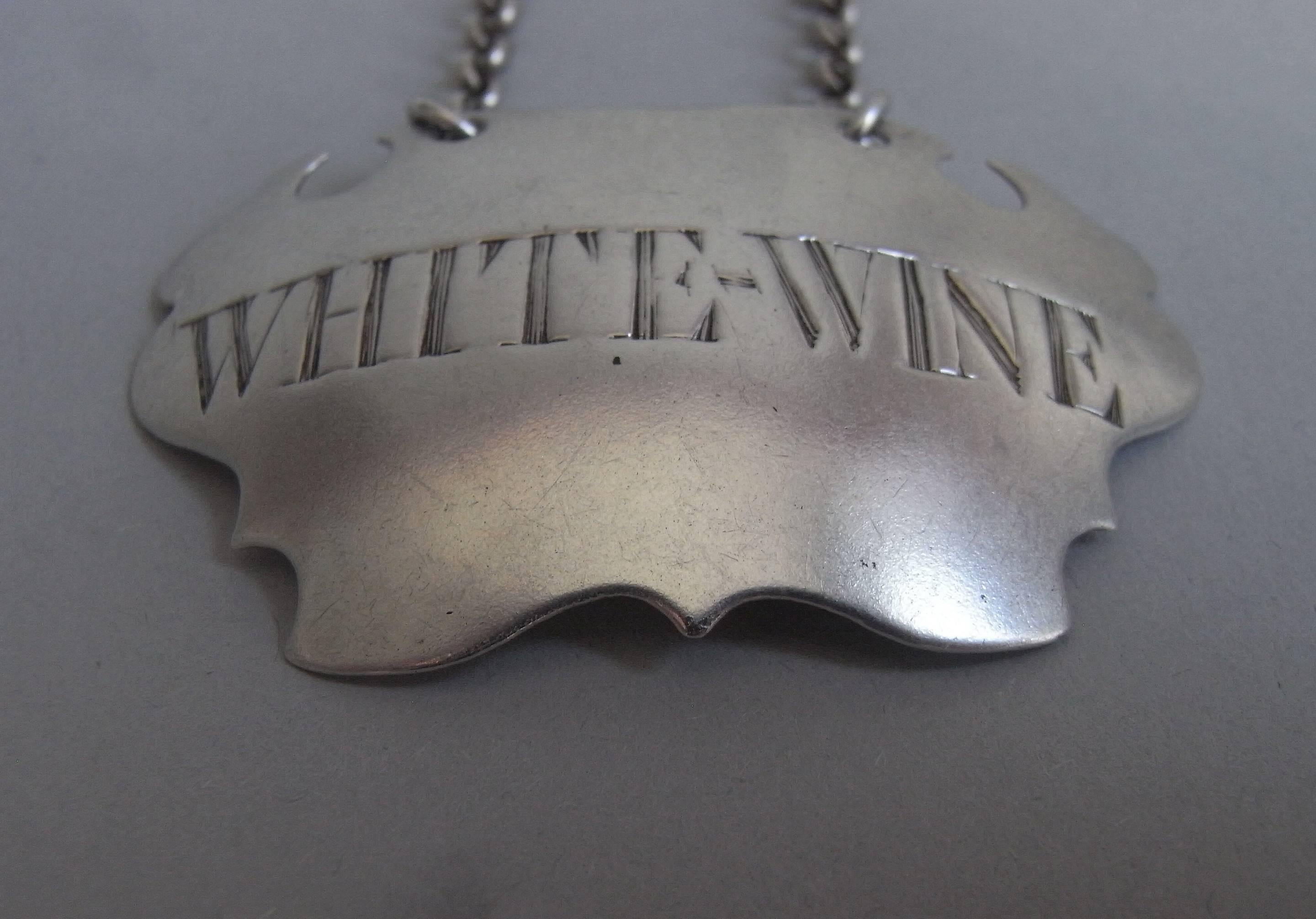 The wine label is of the plain escutcheon style and is engraved for WHITE WINE. This piece is in excellent condition and is very well marked. 

Measures: Length: 2.1 inches, 5.25cm. 
Width: 1.45 inches, 3.63cm.