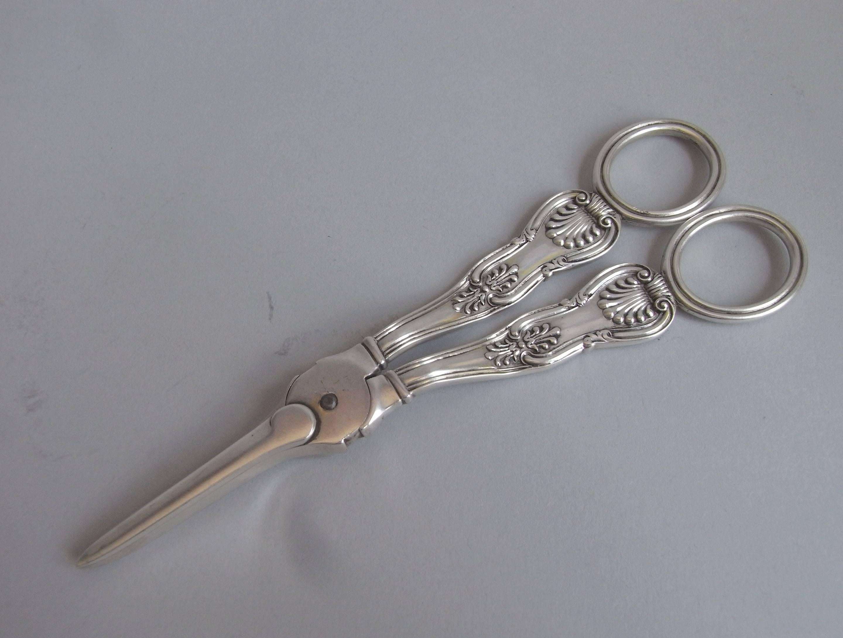 The Grape Shears are of typical form and are modelled in the Kings pattern, which is shown on both the front and the reverse. The oval finger grips are decorated with reeding and one of the arms is engraved with a contemporary crest. The shears are