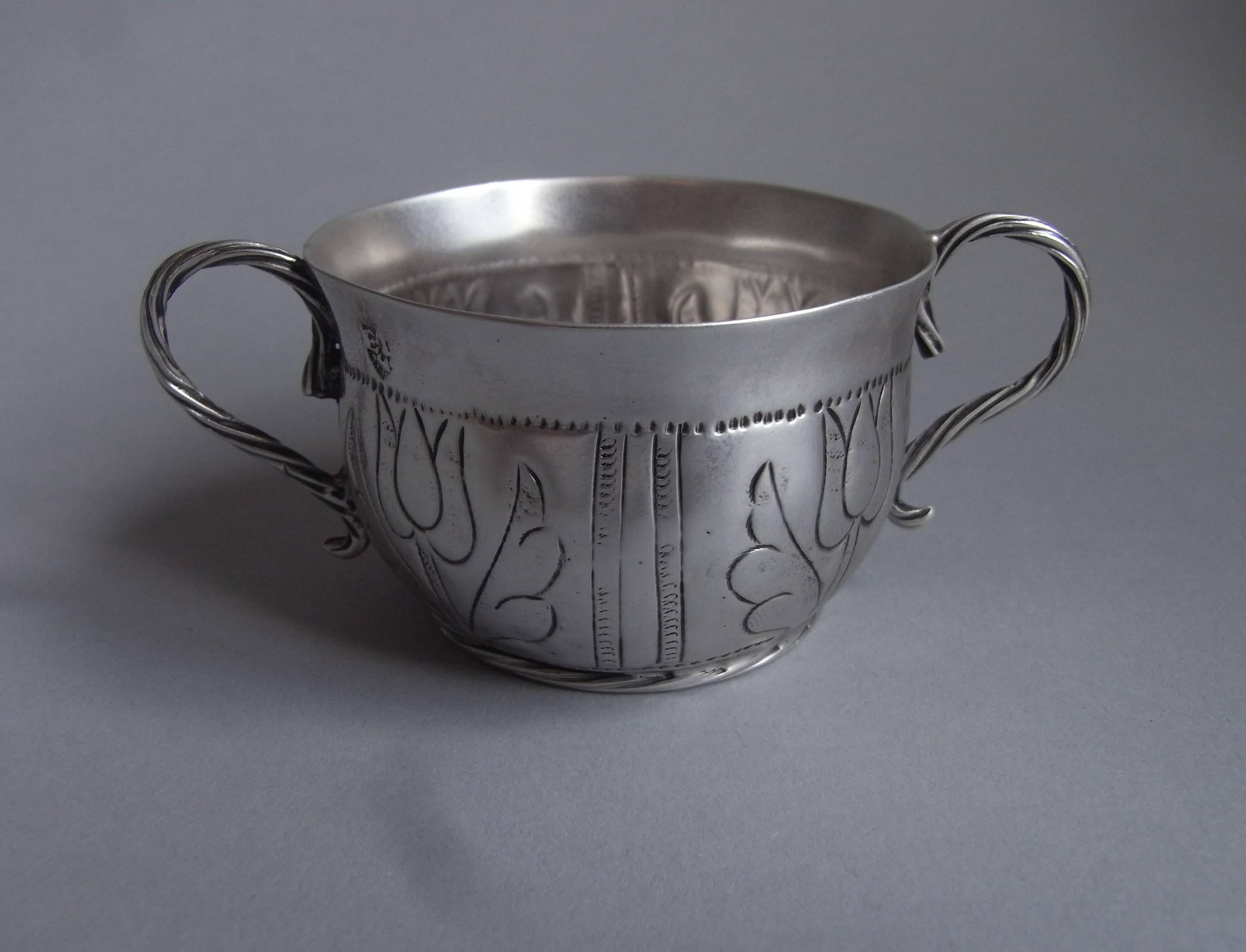 A very rare Commonwealth two handled Cup, most probably a wine taster, made in London in 1655, maker's mark of et, with a crescent below.
This piece is modelled on the design of the larger porringers and stands on an unusual circular applied