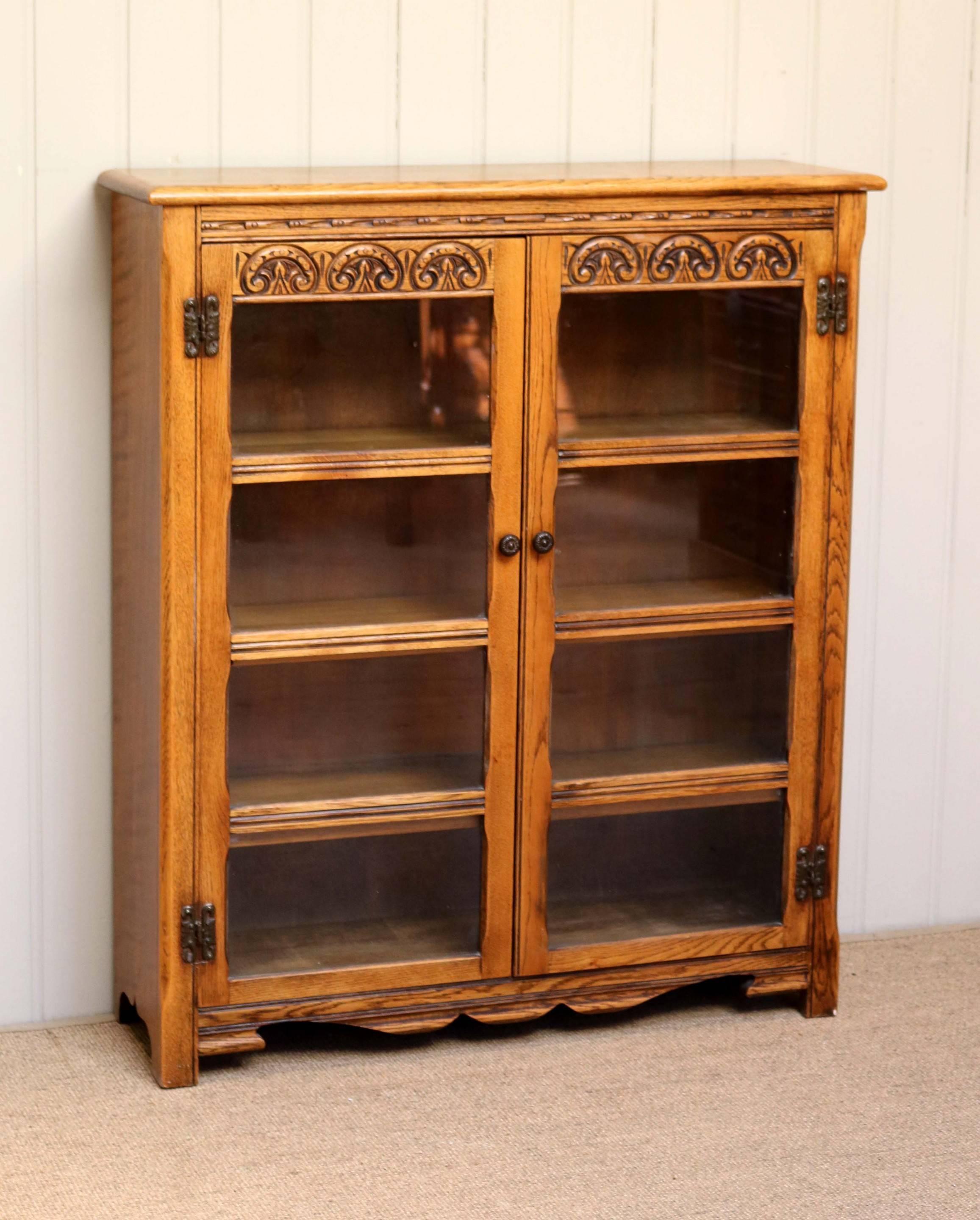 Solid light oak two-door glazed bookcase having three fixed internal shelves raised on block feet.