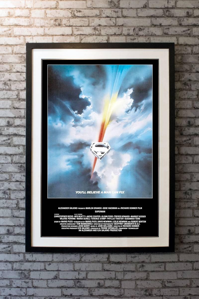 Christopher Reeve stars with Marlon Brando and Gene Hackman in this multi-oscar nominated blockbuster. You'll believe a man can fly! This is the sought after poster with artwork by Bob Peak, from the first release in America. 

Framing