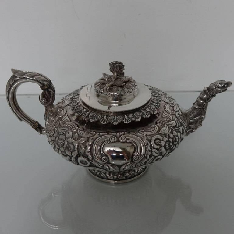 A stunningly beautiful large circular Irish silver teapot, beautifully floral embossed throughout with ornately shaped double cartouches. The spout of the teapot is uniquely designed with a sea serpent theme. The handle is scroll formed with