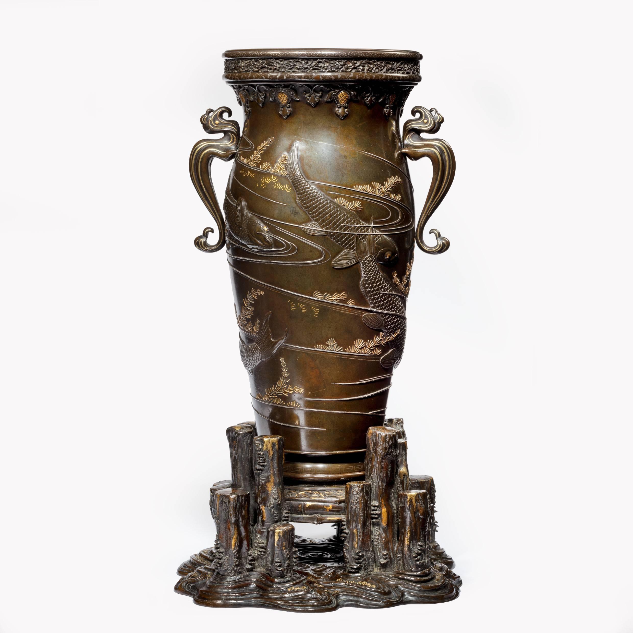 A pair of exhibition quality Meiji period bronze vases each of baluster form with stylized ho-ho bird handles, decorated throughout with large high-relief carp swimming amongst swirling silver ripples and tufts of gilt water weed, the carp with gilt
