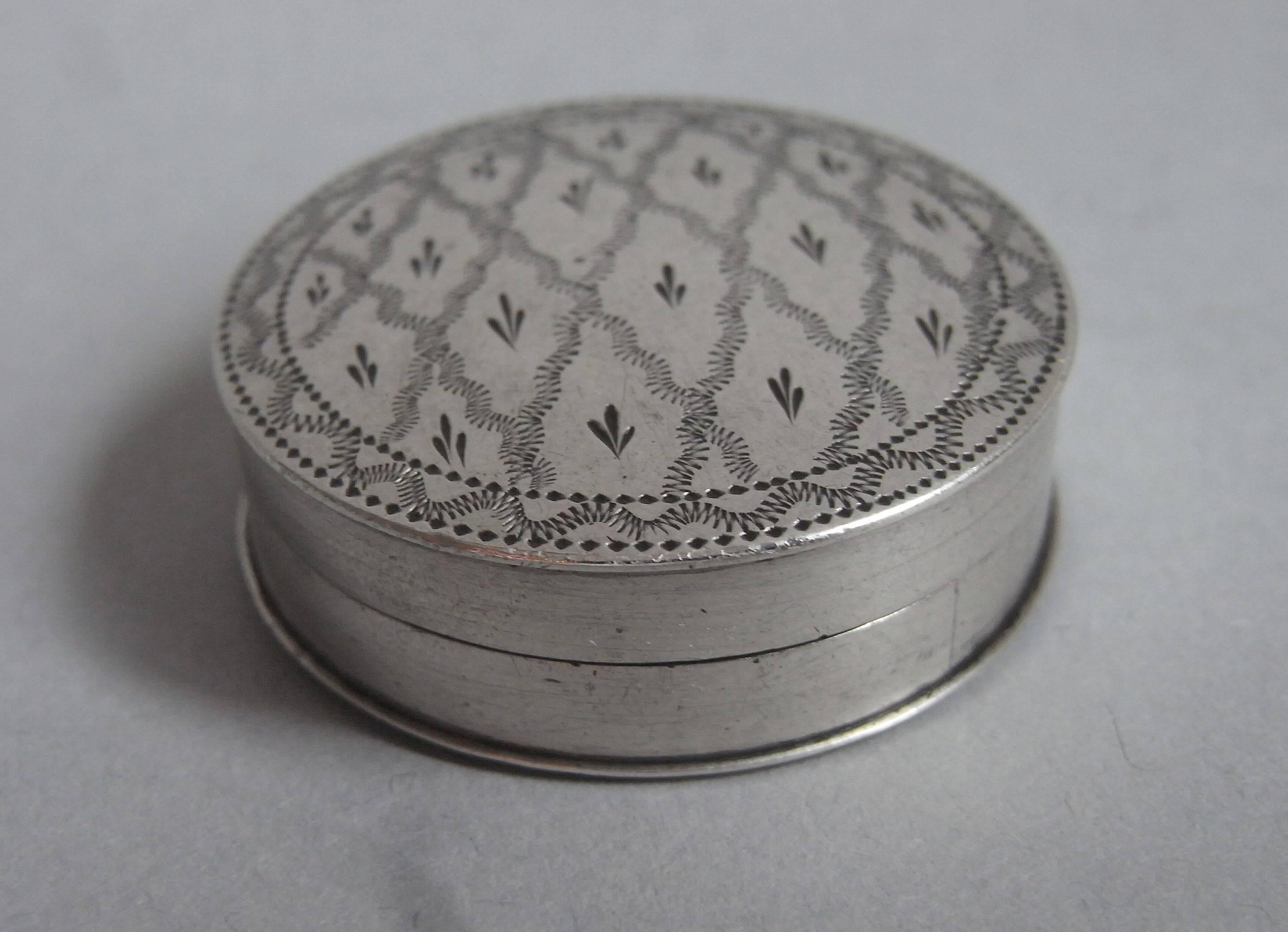 The patch box is circular in form with a pull off cover. The cover is beautifully decorated with unusual trellis work designs containing tri-furcated sprigs. The base displays an outer wavy prick dot border. The box is somewhat larger than usually