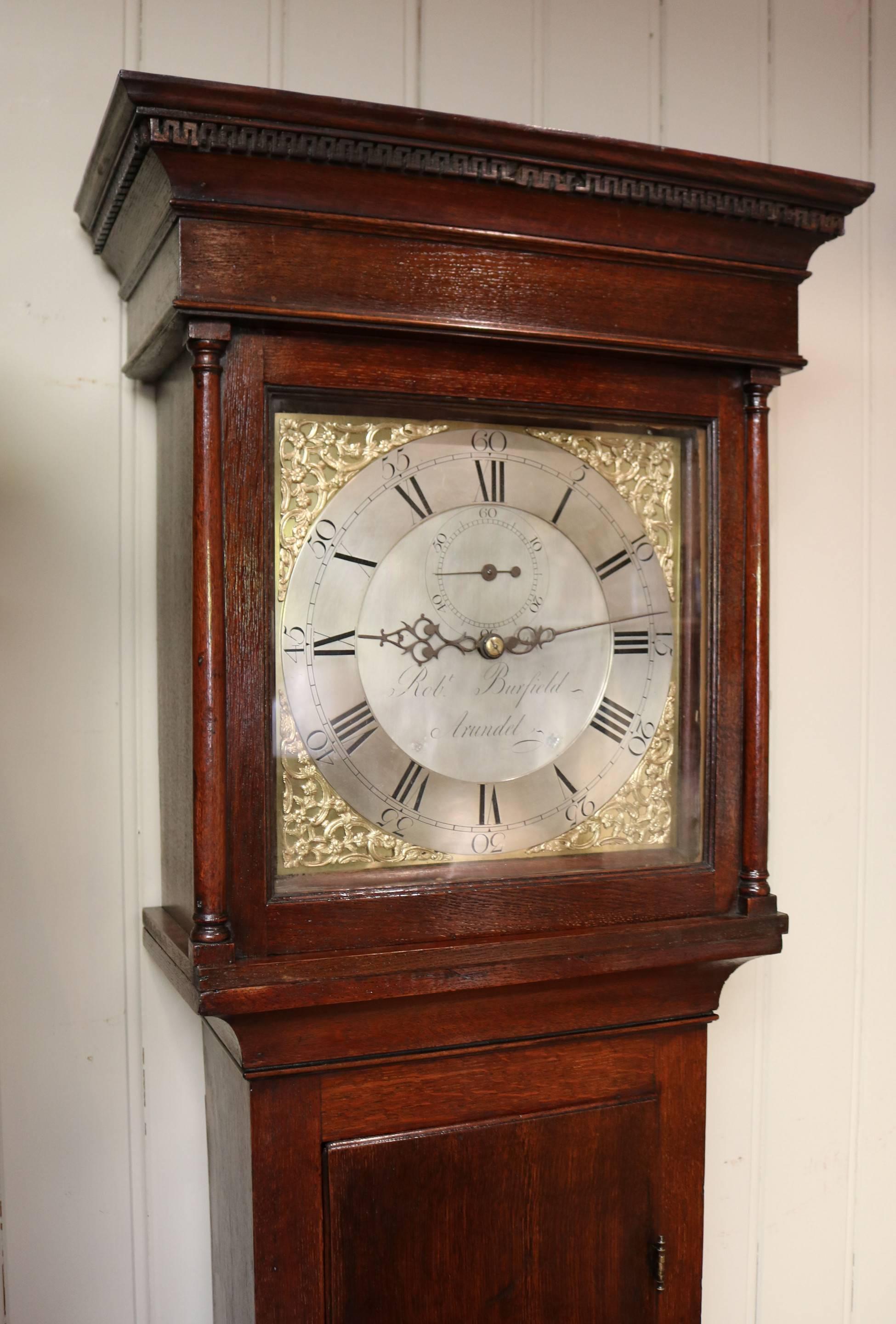 A very original Sussex made country longcase clock. The solid oak case has a dental top molding, turned side pillars and a long door. The brass dial has corner spandrels, a silvered chapter ring and a silvered centre, engraved with the makers name