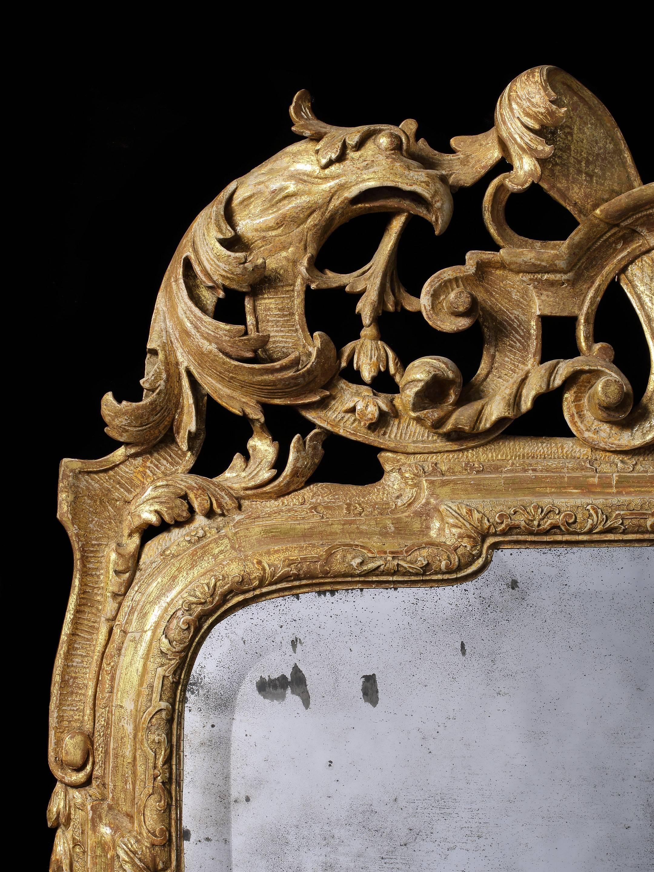 The mirror retains the original shaped and bevelled mirror plate and most of the original gesso and gilding. The glass arms, sockets and supports are restorations.