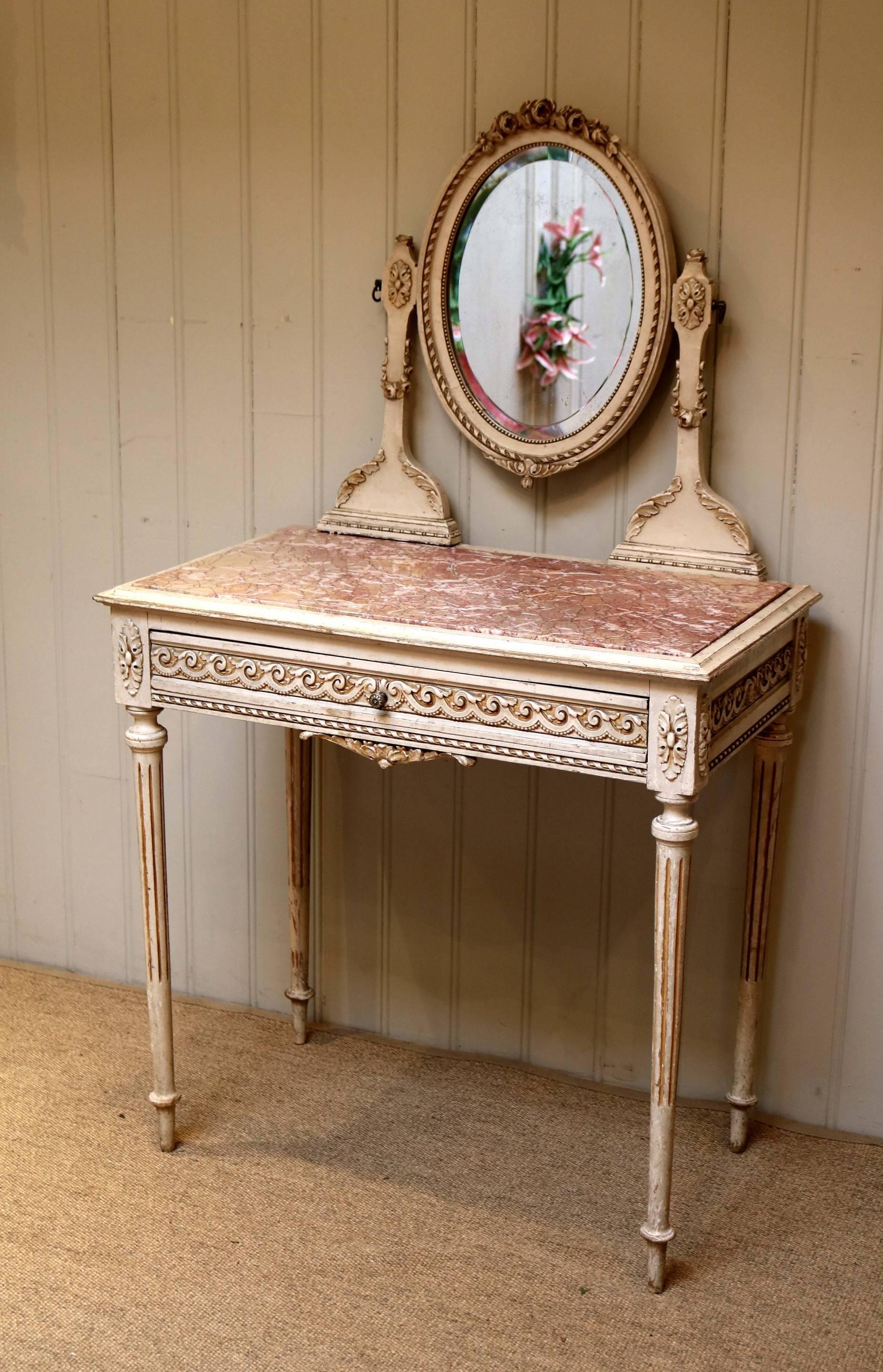 French painted dressing table having the original paint finish with an oval dressing mirror with applied heart decoration supported by carved supports above a rouge marble top and single carved drawer raised on tapering reeded legs.