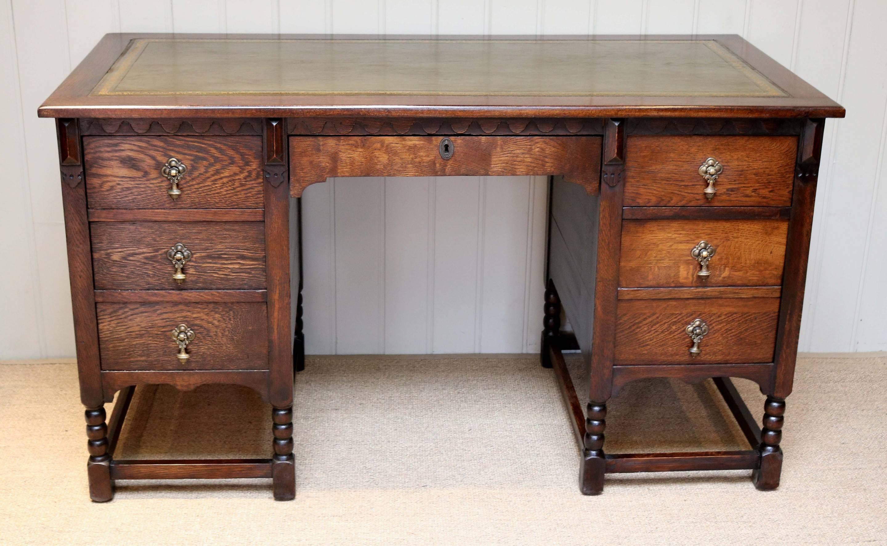 Large oak desk with single central drawer, flanked either side by three drawers, set below a carved oak top with leather scriber. Raised on bobbin turned supports.