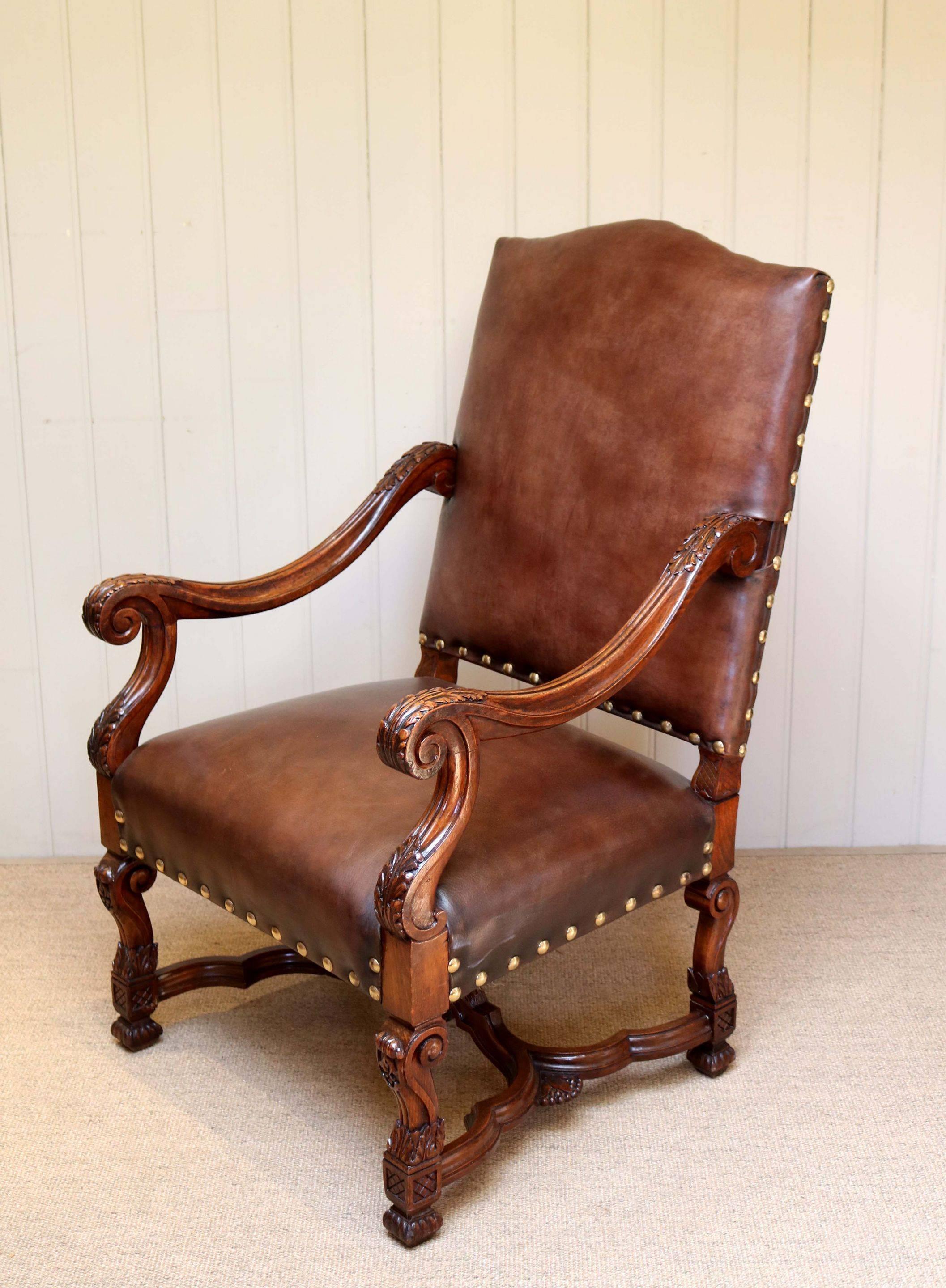Substantial French beechwood open armchair having a turned wooden frame with carved arm supports and reupholstered in a high grade leather on the seat and back.