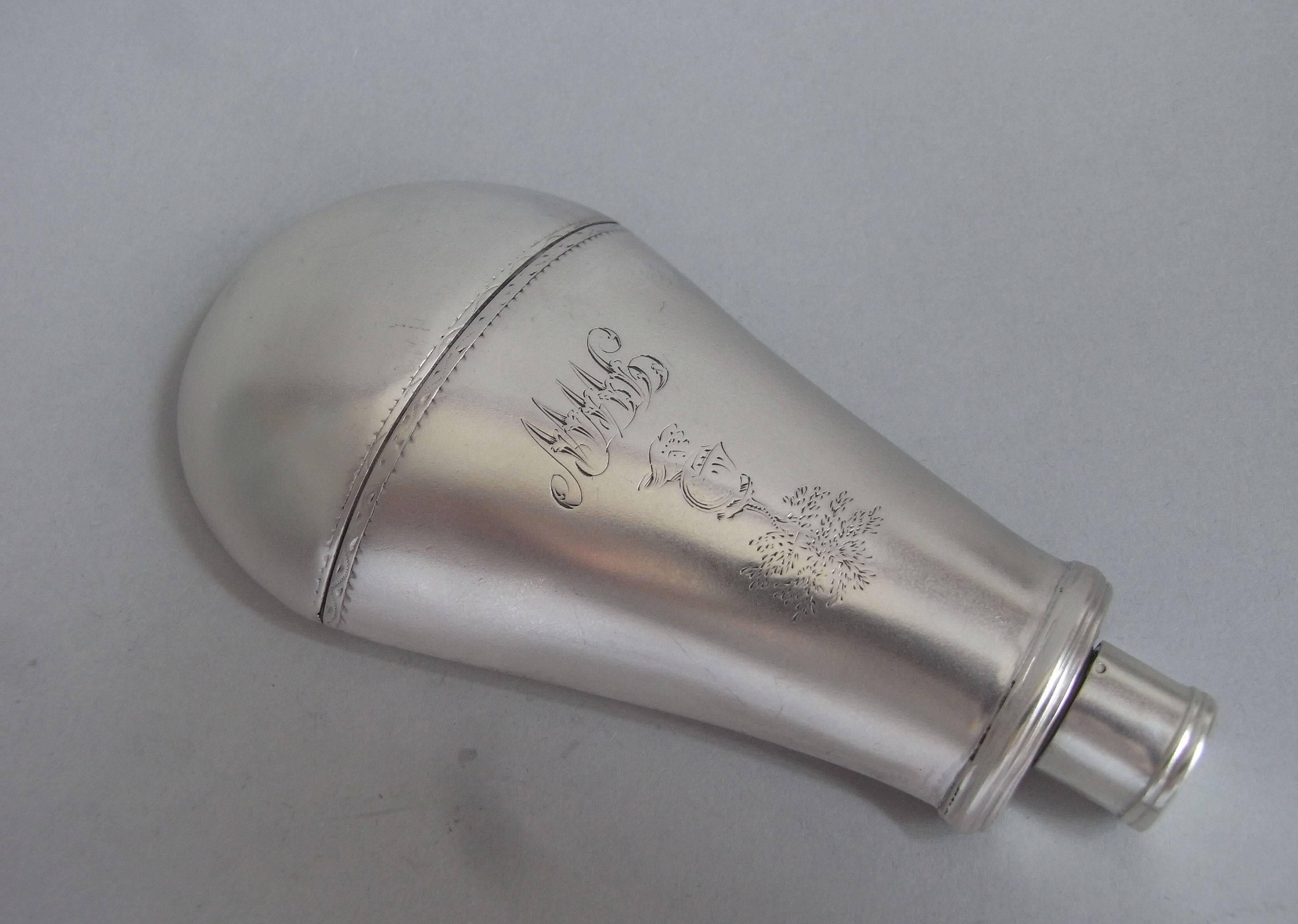 This very fine drinking flask is unusually and realistically modelled as a gun powder flask. The main body is engraved with bright cut borders, as well as a contemporary crest, with script initials below. The reeded cap unscrews so that the contents