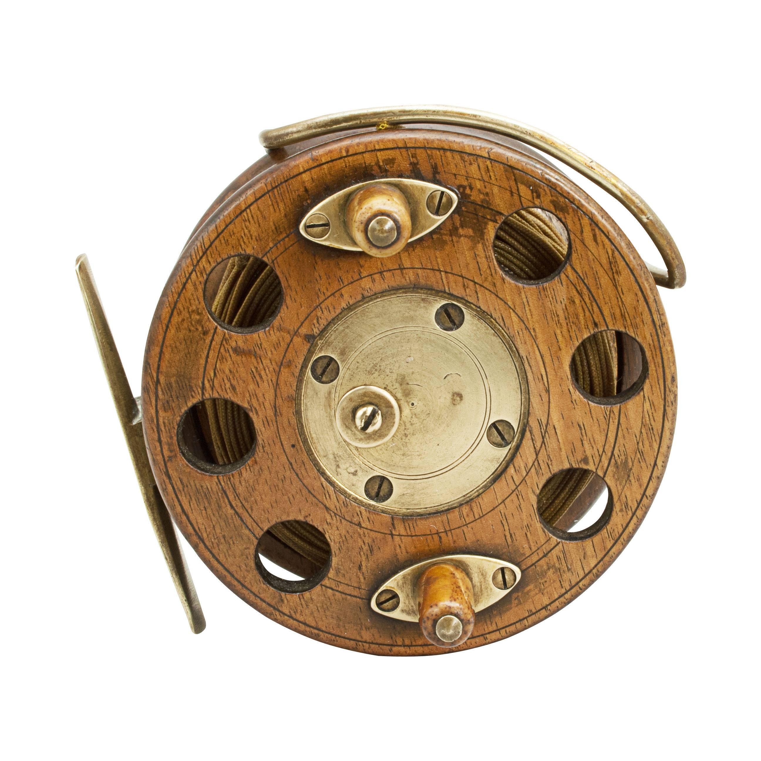 A fine walnut centre pin starback fishing reel with cut out holes and two bone handles in the front plate. The drum with brass quick release mechanism. Also with line guard, optional check and silk line.