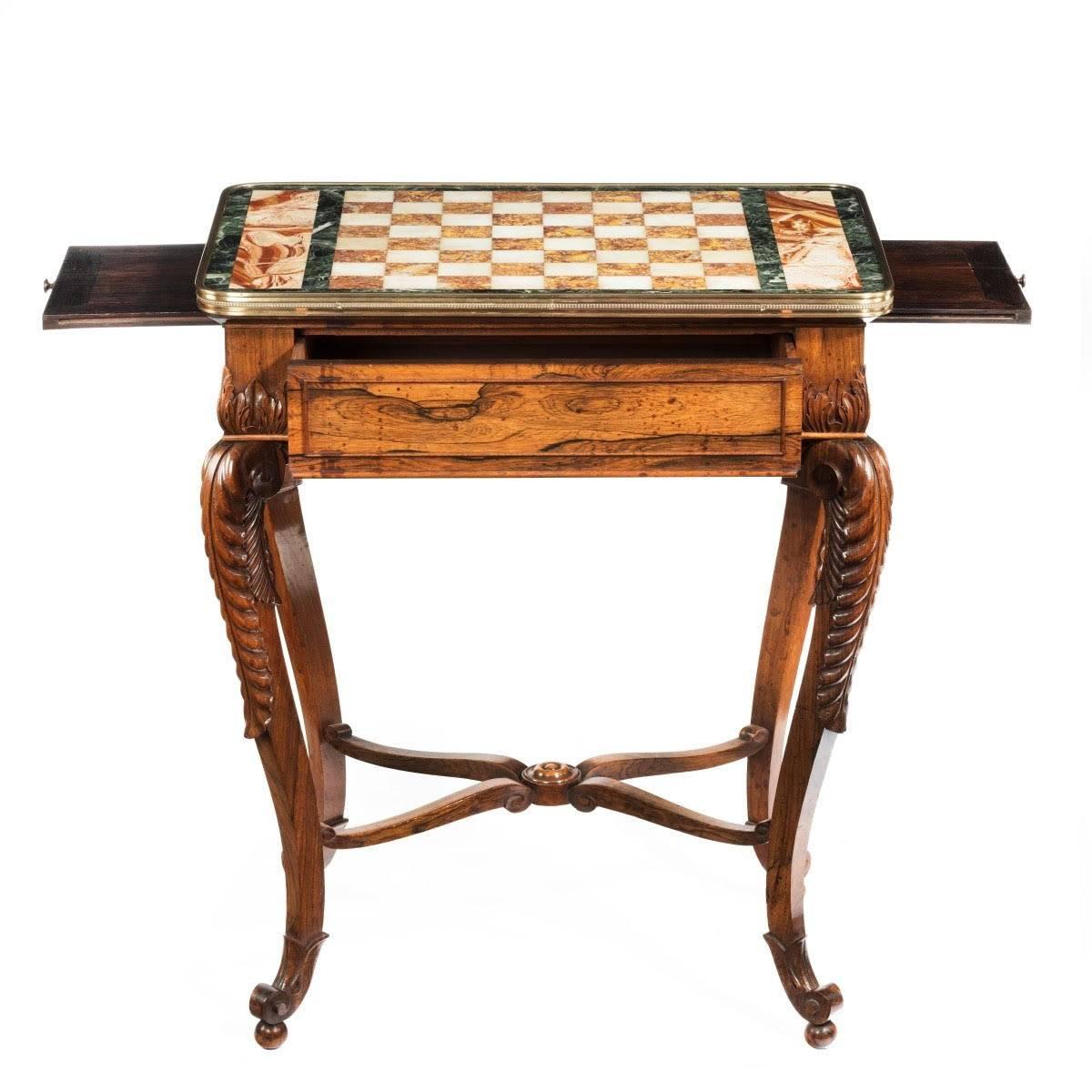 The rectangular top with a chess board of white and rose/yellow sienna marble, within grey borders and a brass edge, the frieze with a central drawer and a slide on either end, the cabriole legs carved with acanthus leaves and terminating in scroll