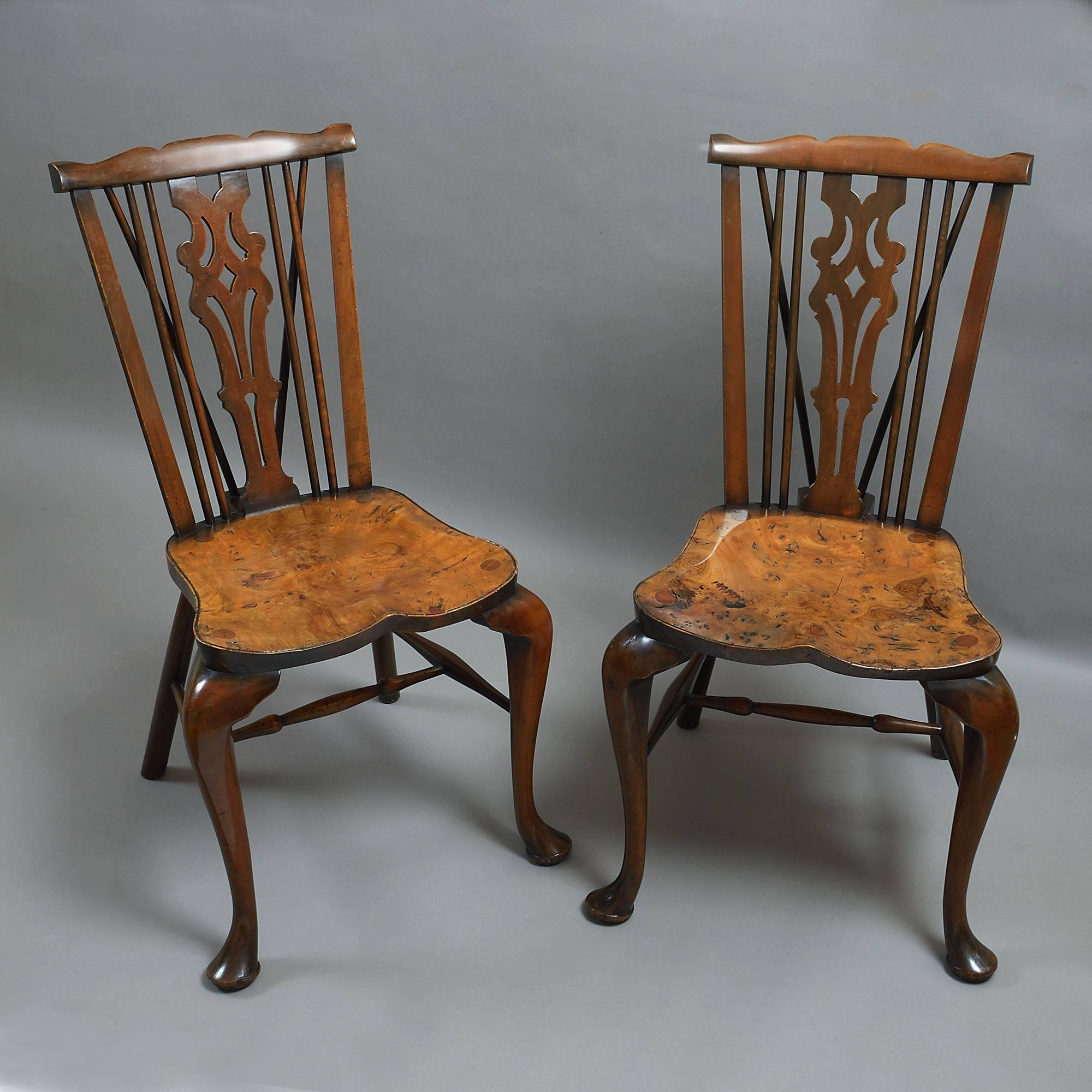 A pair of early 20th century yew wood hall chairs, having Windsor backs, finely figured burr yew saddle seats all raised upon turned legs with stretchers.