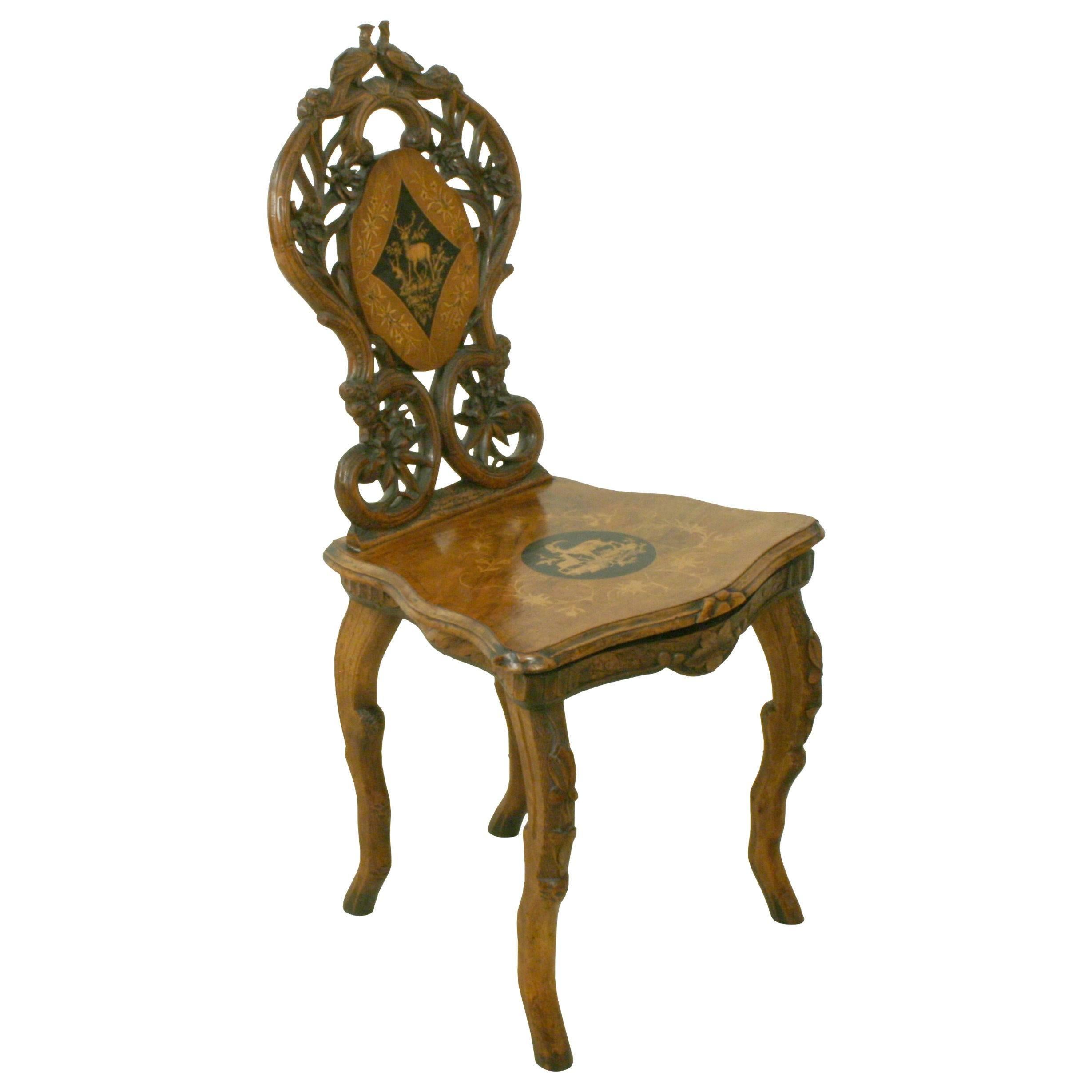 Black Forrest carved wooden musical chair.
A richly carved walnut Black Forest musical chair with pierced back and delicate inlays. The back with central oval portion with inlaid image of a stag and floral designs, outer portion with hand-carved