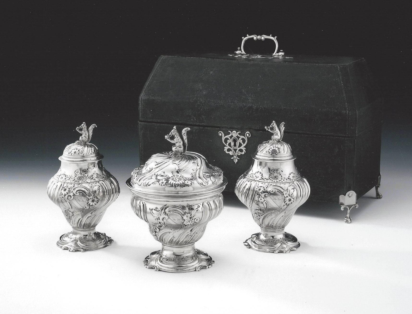 The tea caddies and sugar bowl stand on a cast shaped foot chased with Rococo scrolls and flower heads. The baluster shaped main bodies are decorated with spiral fluting, as well as floral sprays. The pull off covers are decorated in the same manner