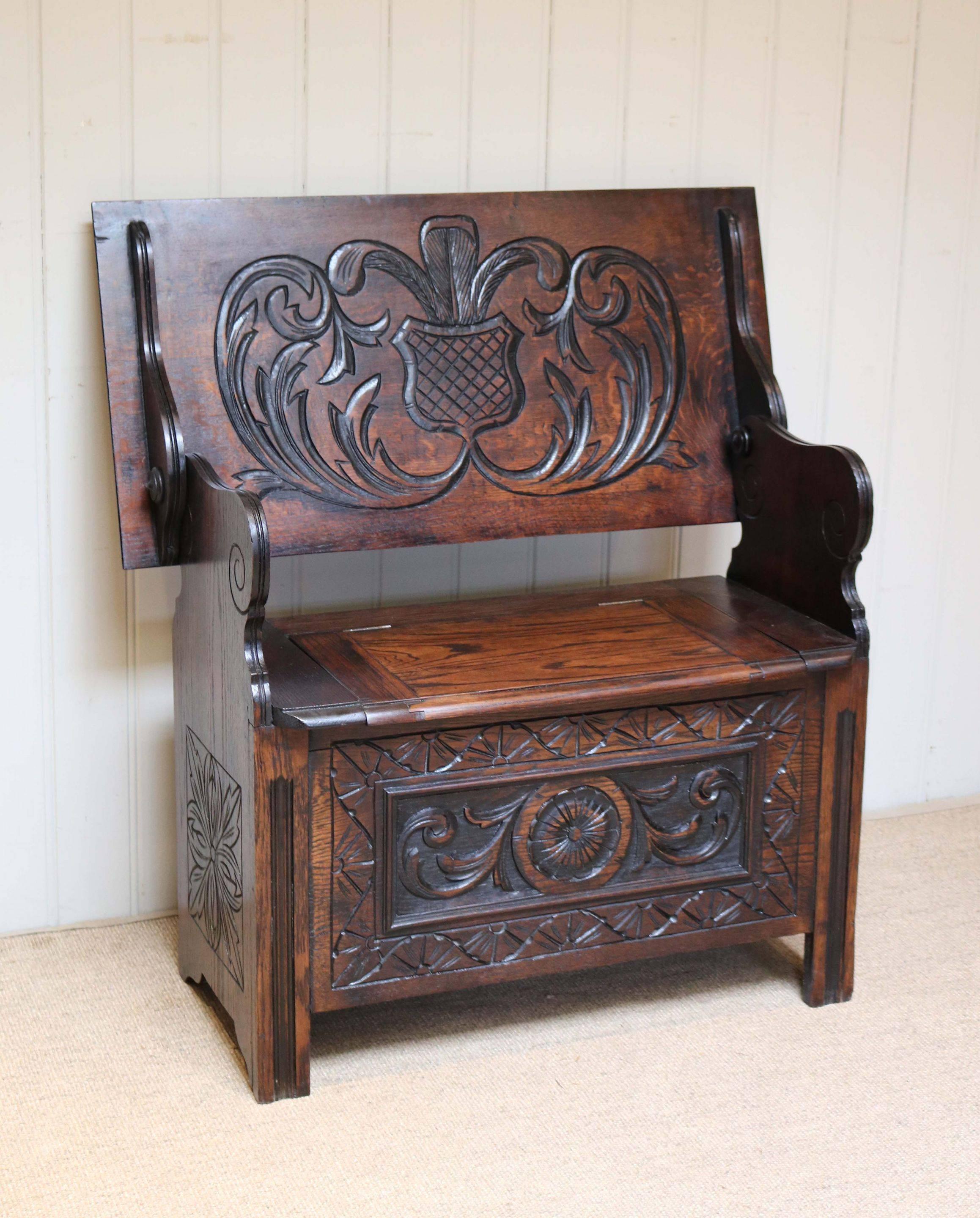 Solid oak monks bench having a carved front panel and sides with a lift up seat for storage with a carved back which folds to become a table with shaped supports The height when folded as a table is 71cm.