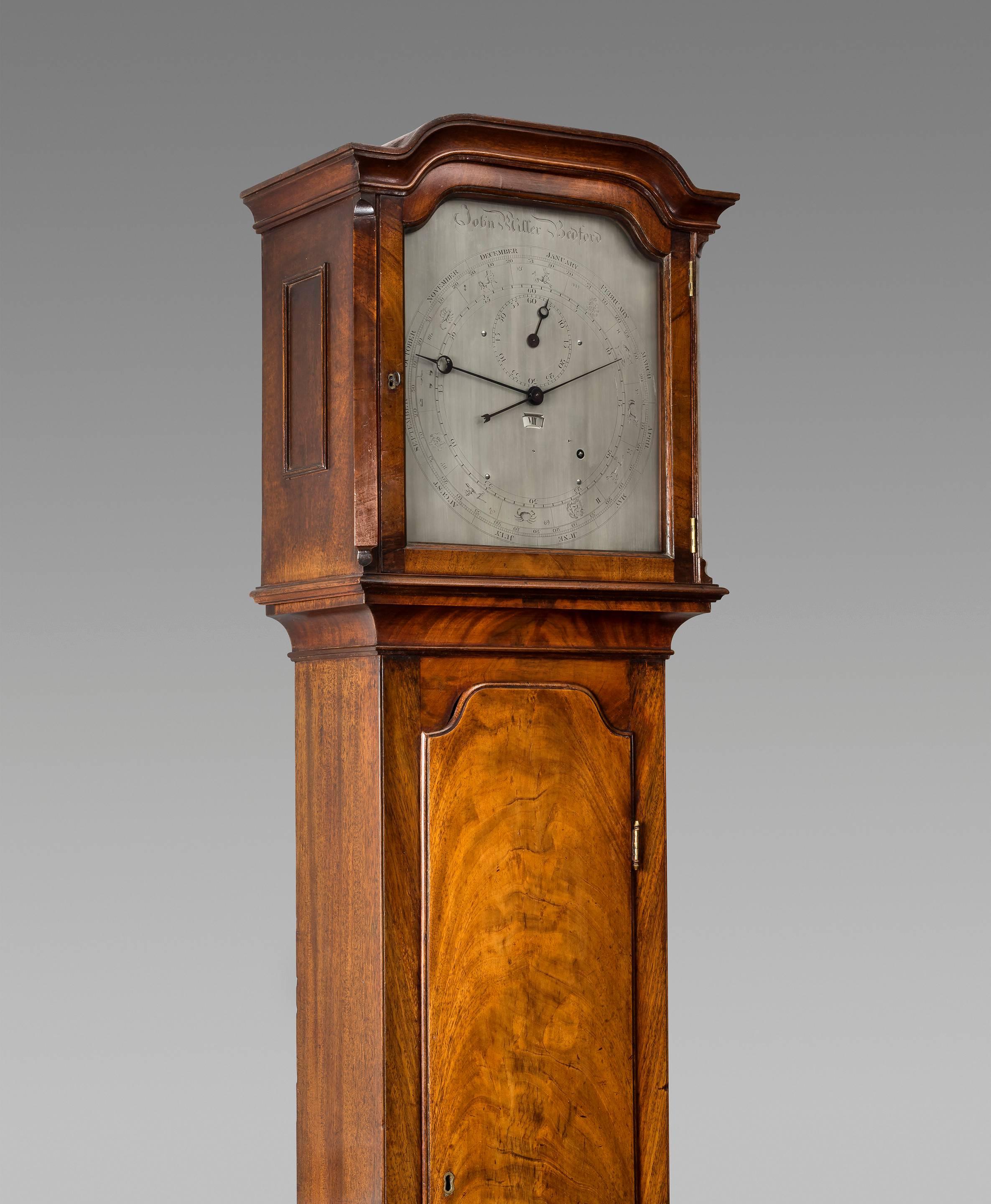 A fine English Regency mahogany regulator longcase, the beautiful flame veneered case with shallow arch and ogee moulded hood. The 12 inch ogee shaped silvered dial is of the regulator type with separate dials for hours, minutes and seconds. It also