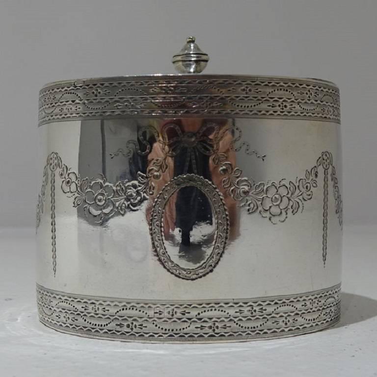 An elegant late 18th century Georgian bright cut engraved tea caddy with flush hinged lid. The caddy has a contemporary double oval cartouche with central floral garlands for decoration around the centre of the body. There are additional upper and