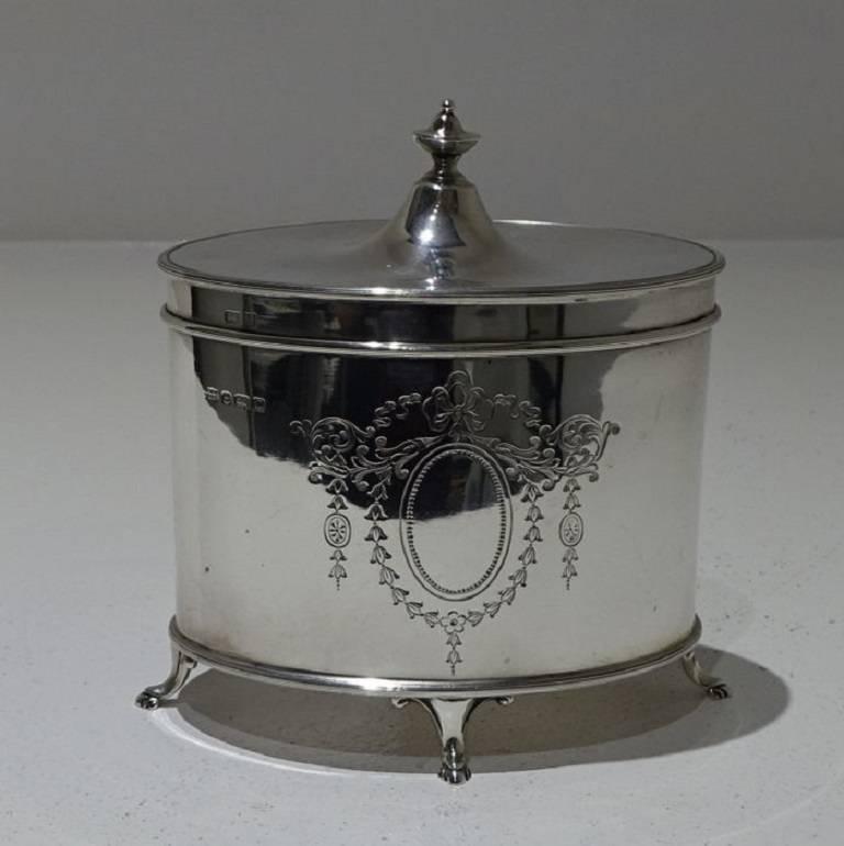 A large stylish 20th century oval tea caddy with hinged lid. The caddy sits on four decorative feet and has a elegant bright cut engraved cartouche on the center front of the body. 
The length is 16.5cm.