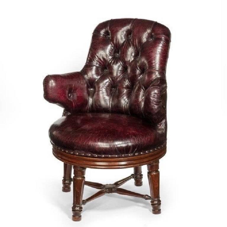 An unusual William IV mahogany revolving desk chair of generous proportions. The deep buttoned back and seat covered in distressed leather, set upon four turned and carved legs with united stretchers.