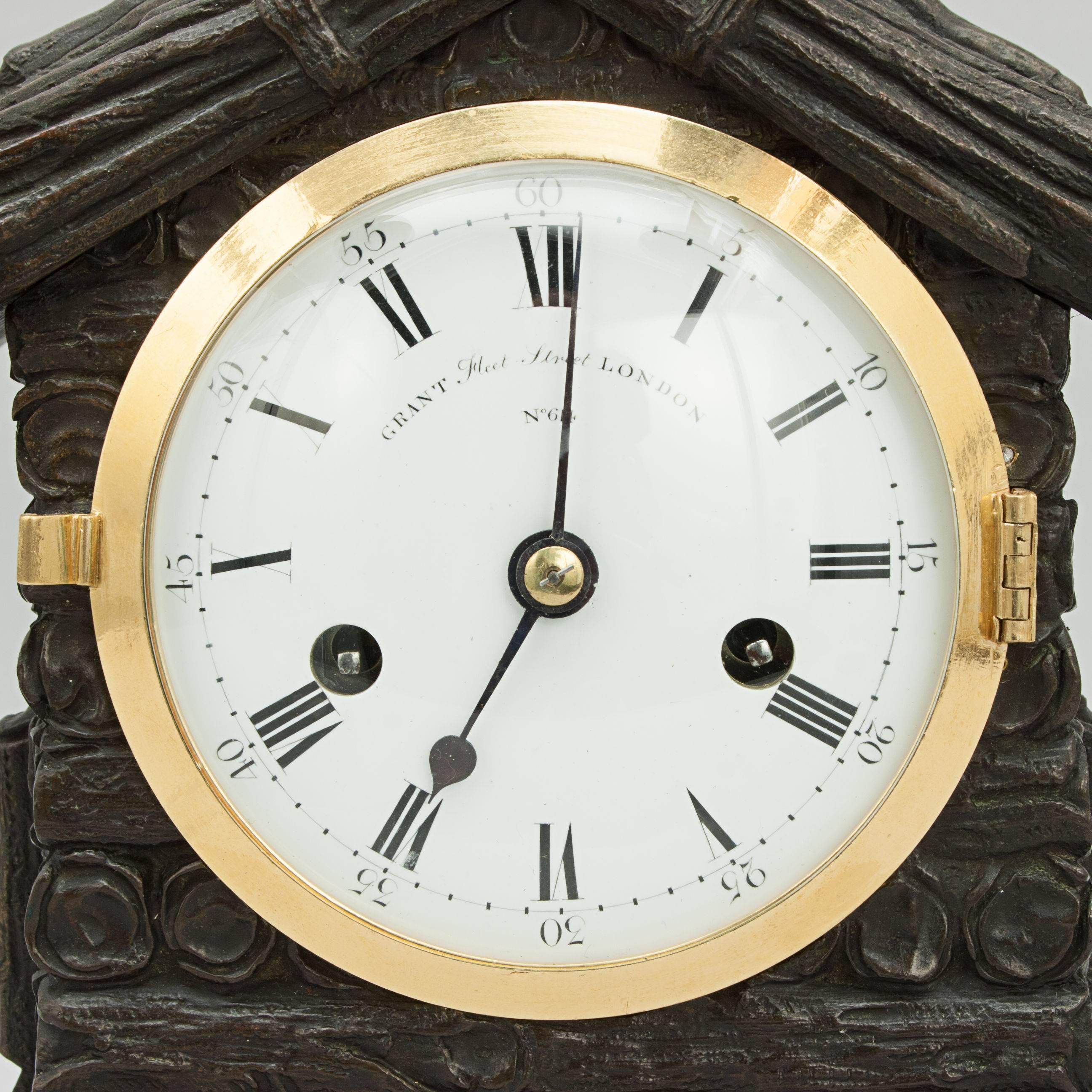 Mantel clock by Grant.
An unusual mantel clock with the heavy bronze case in the form of a log cabin. The clock workings by John Grant, Fleet Street, London. The 4' diameter white enamel bowed dial, with black Roman numerals for the hours and
