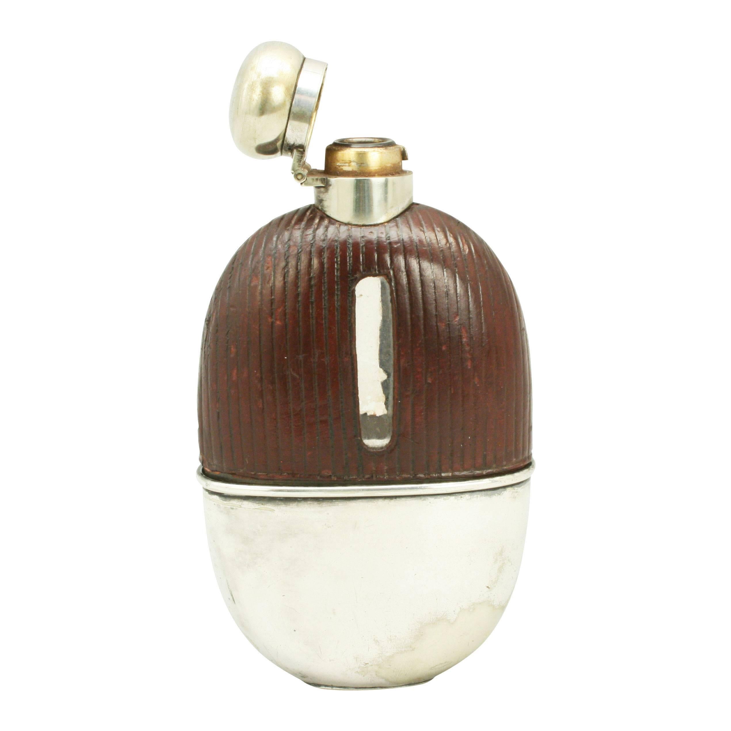 A very nice silver plate spirit hip flask with the top half covered in leather with level viewing windows cut into both sides. The flask with hinged lid with screw bayonet fitting, the bottom with a removable drinking cup. A very nice shaped flask.