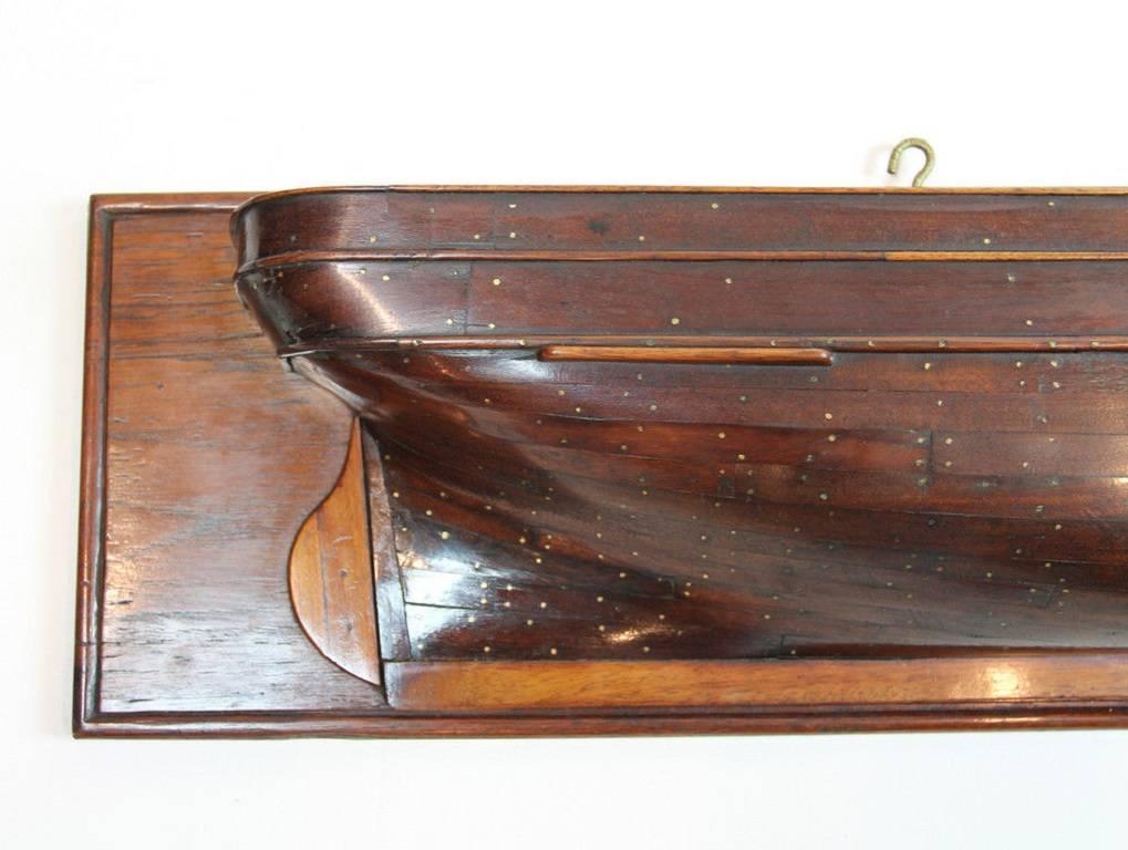 Unusual shipbuilder's half-block model of a sailing ship with simulated pinned and veneered planking on a solid hull on a polished teak back-board.