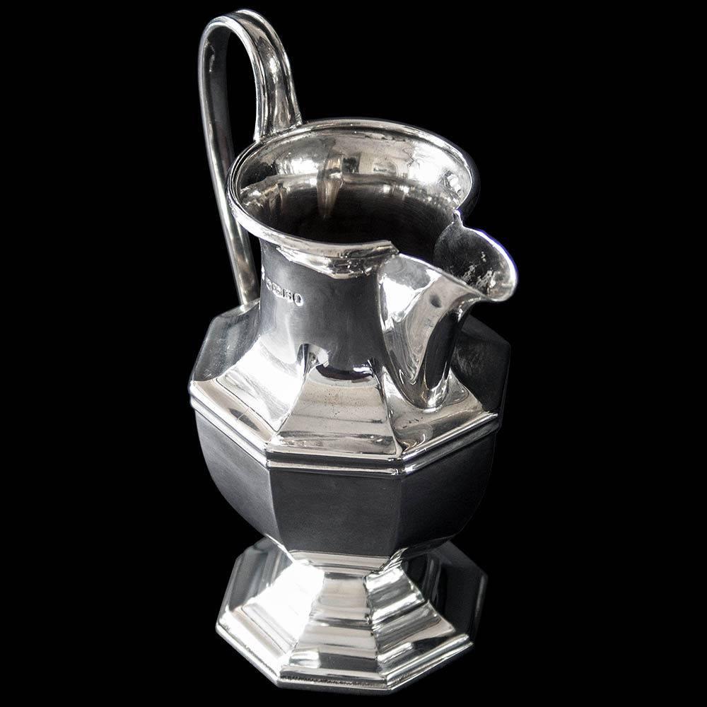 A sterling silver octagonal shaped cream jug on pedestal foot with sparrow beak spout.