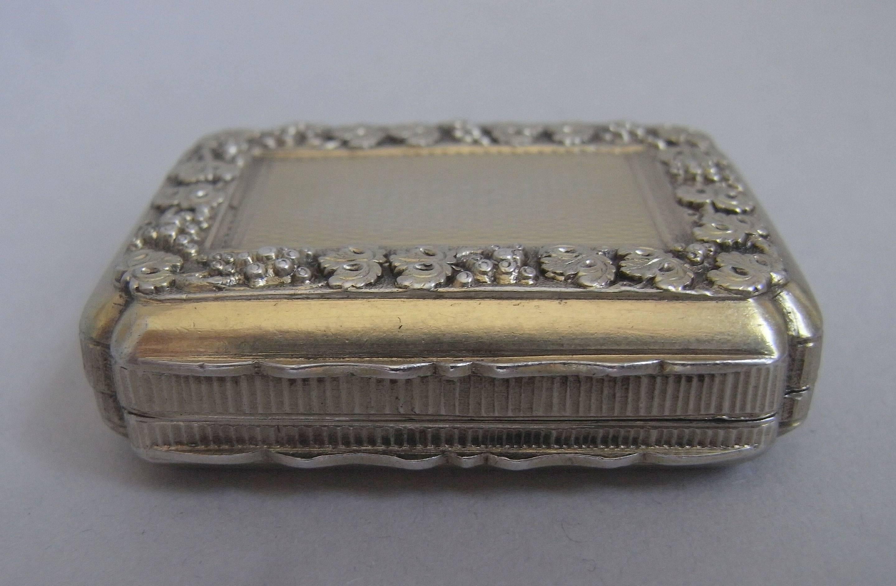 The Vinaigrette is broad rectangular in form, with incuse corners. The cover is most unusually decorated with an outer border of raised trailing vines and grapes, surrounding an engine turned panel. The sides display a serpentine shaped thumb piece