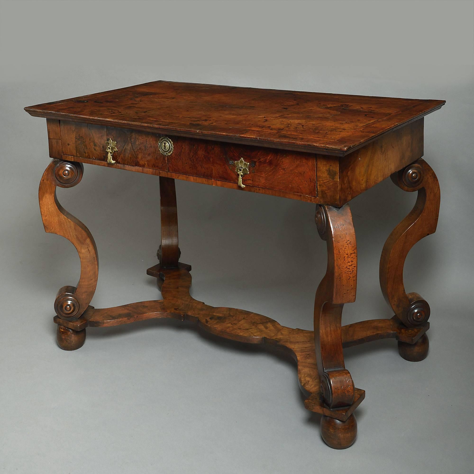 A Charles II period burr walnut side table, the quarter veneered top with herringbone inlay and crossbanding above a single drawer with flower petal brass lock escutcheon and drop handles, all supported upon S-scroll legs, conjoined by a shaped