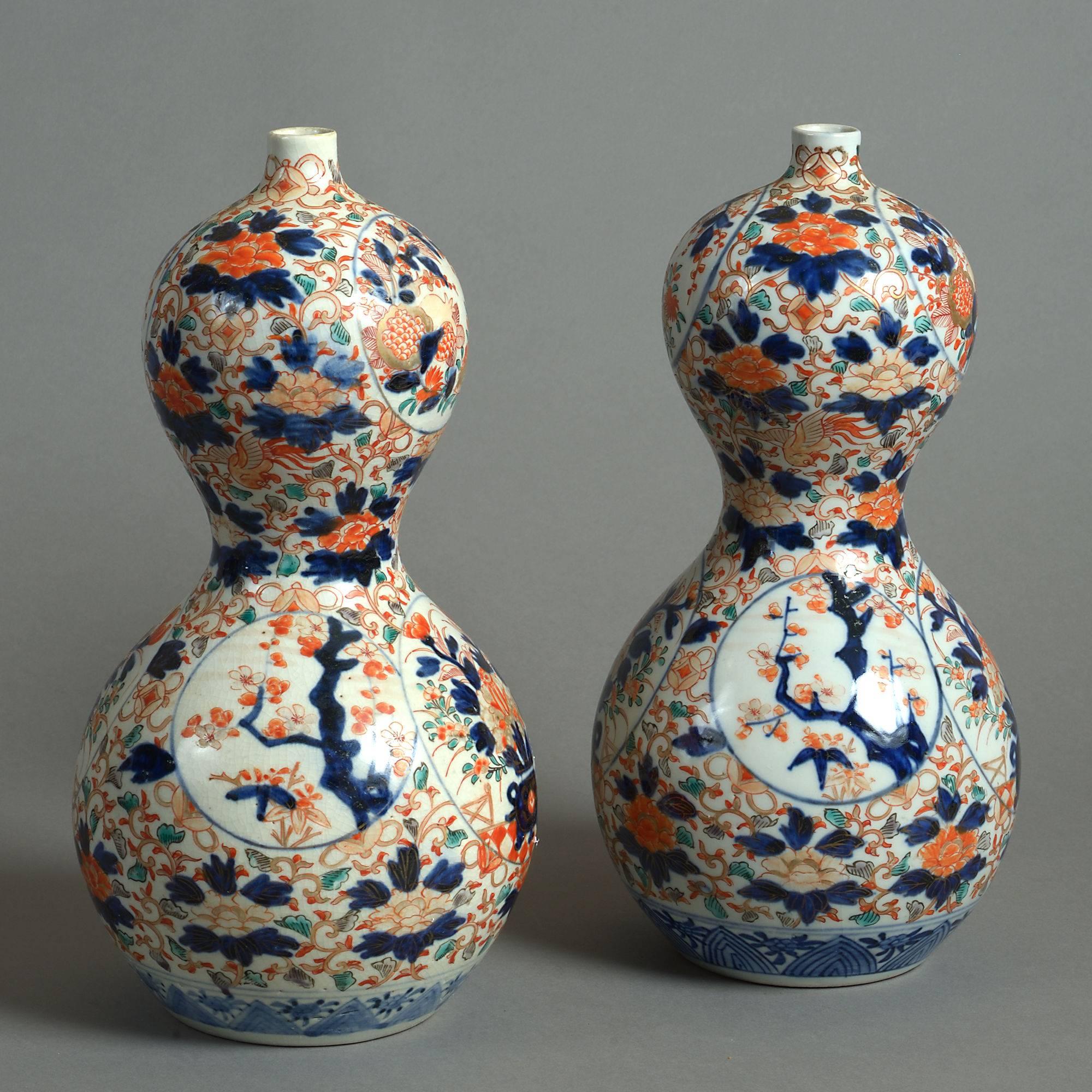 A pair of late 19th century Imari porcelain gourd vases, both decorated throughout with cartouches of floral and foliate motifs upon a ground of the same.

Meiji period.