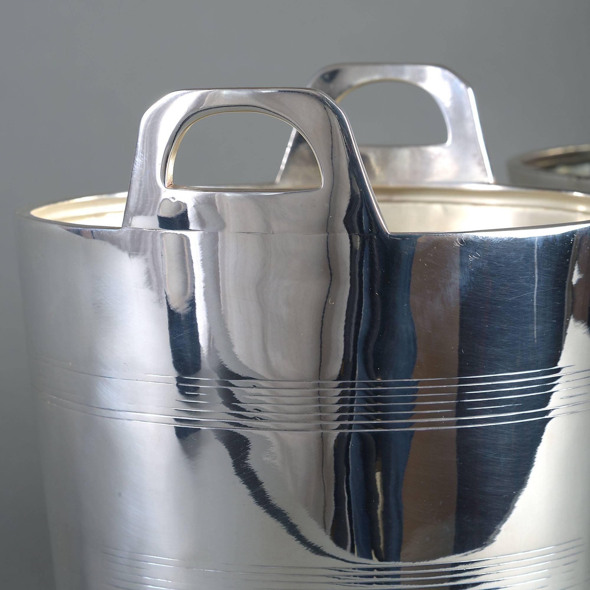 A pair of early 20th century silver plated ice pails, the bodies with turned rings and having two carrying handles. 

One with stamps for Lyons Corner Houses to the underside.
