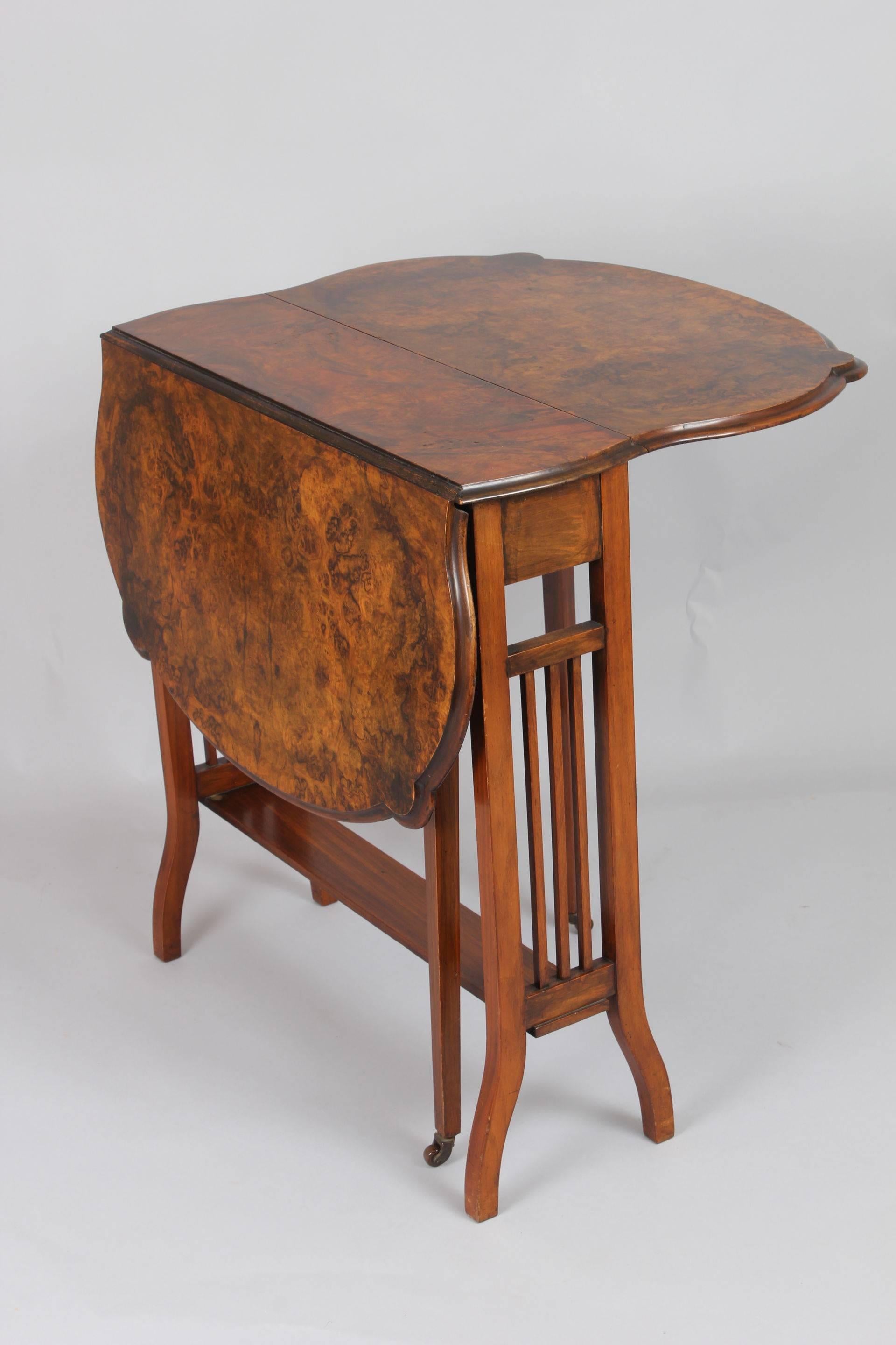 Edwardian walnut Sutherland table; the shaped top with matched burr veneers, on agate-leg frame with slatted end-standards.