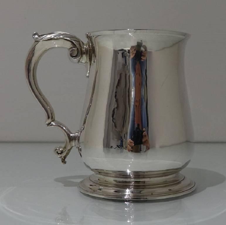 An elegant plain formed 18th century silver pint mug with double scroll handle which is crowned with a beautiful acanthus leaf thumb piece.