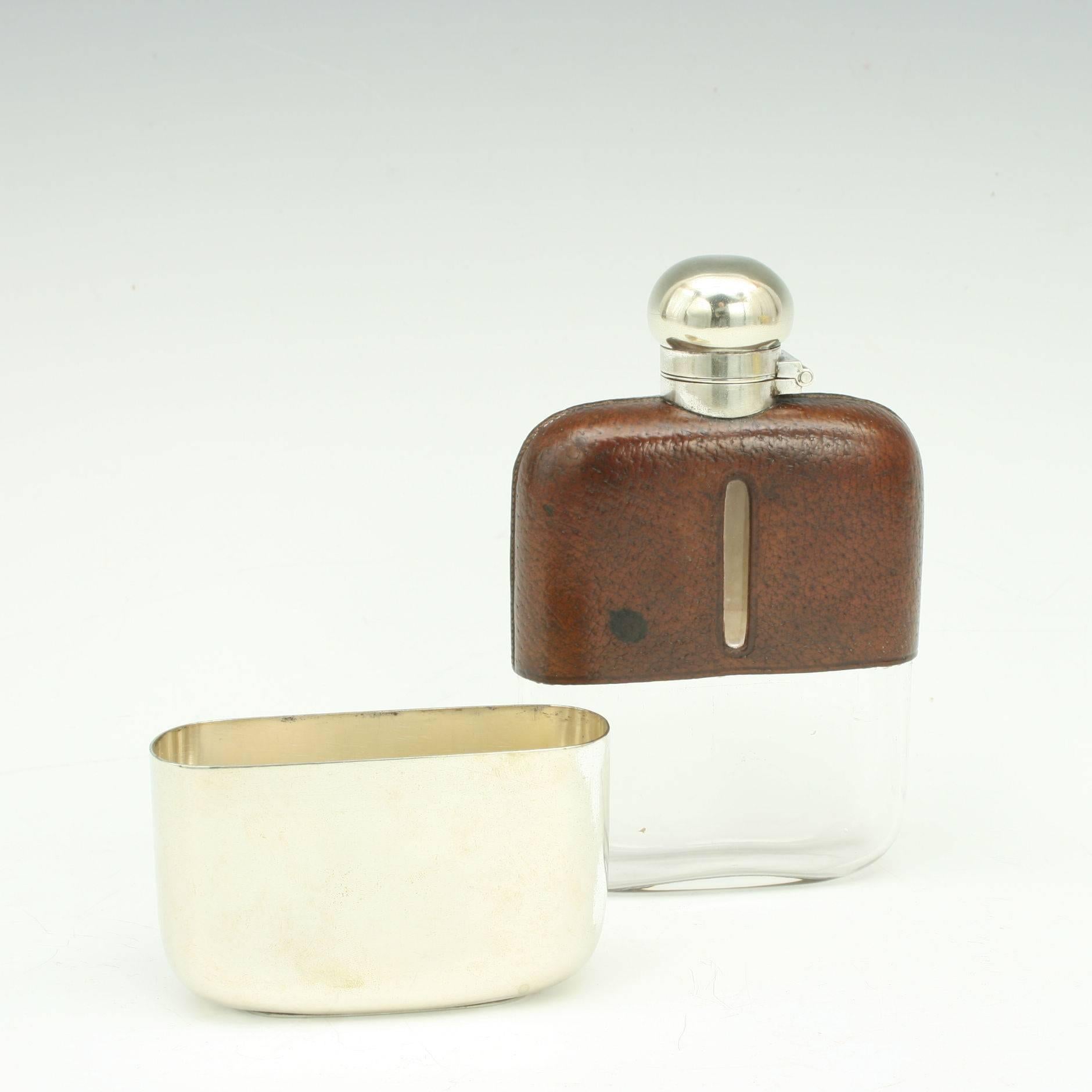 Gentleman's Hip Flask. 
A very nice silver plate spirit hip flask with the top half covered in leather with level viewing windows cut into both sides. The flask with hinged lid with screw bayonet fitting, bottom with a removable drinking cup. The