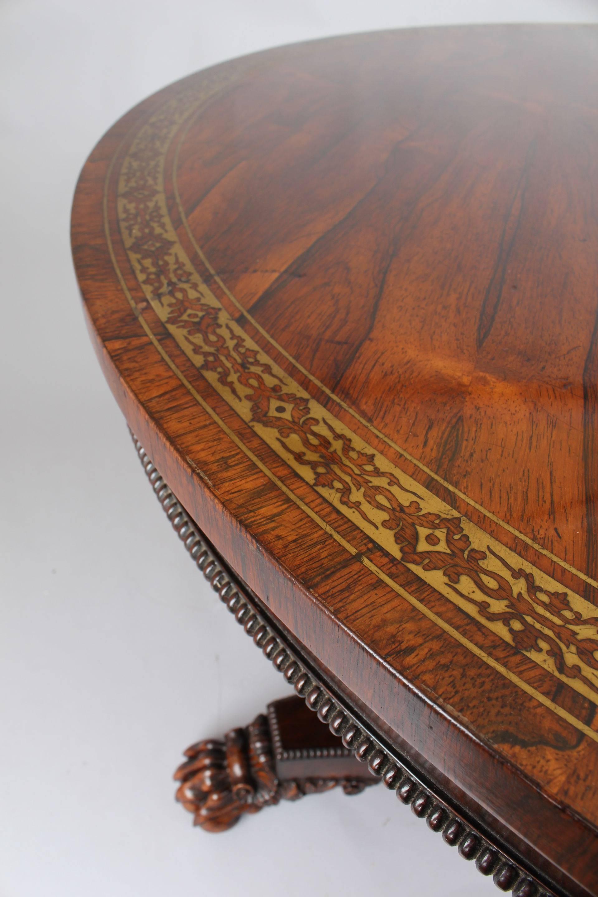 Fine and classic Regency rosewood pedestal table in the manner of Gillows of Lancaster; the circular well-figured top with a narrow border of cut-brass scrollwork, on an hexagonal tapering shaft and a triangular platform base with knulled mouldings