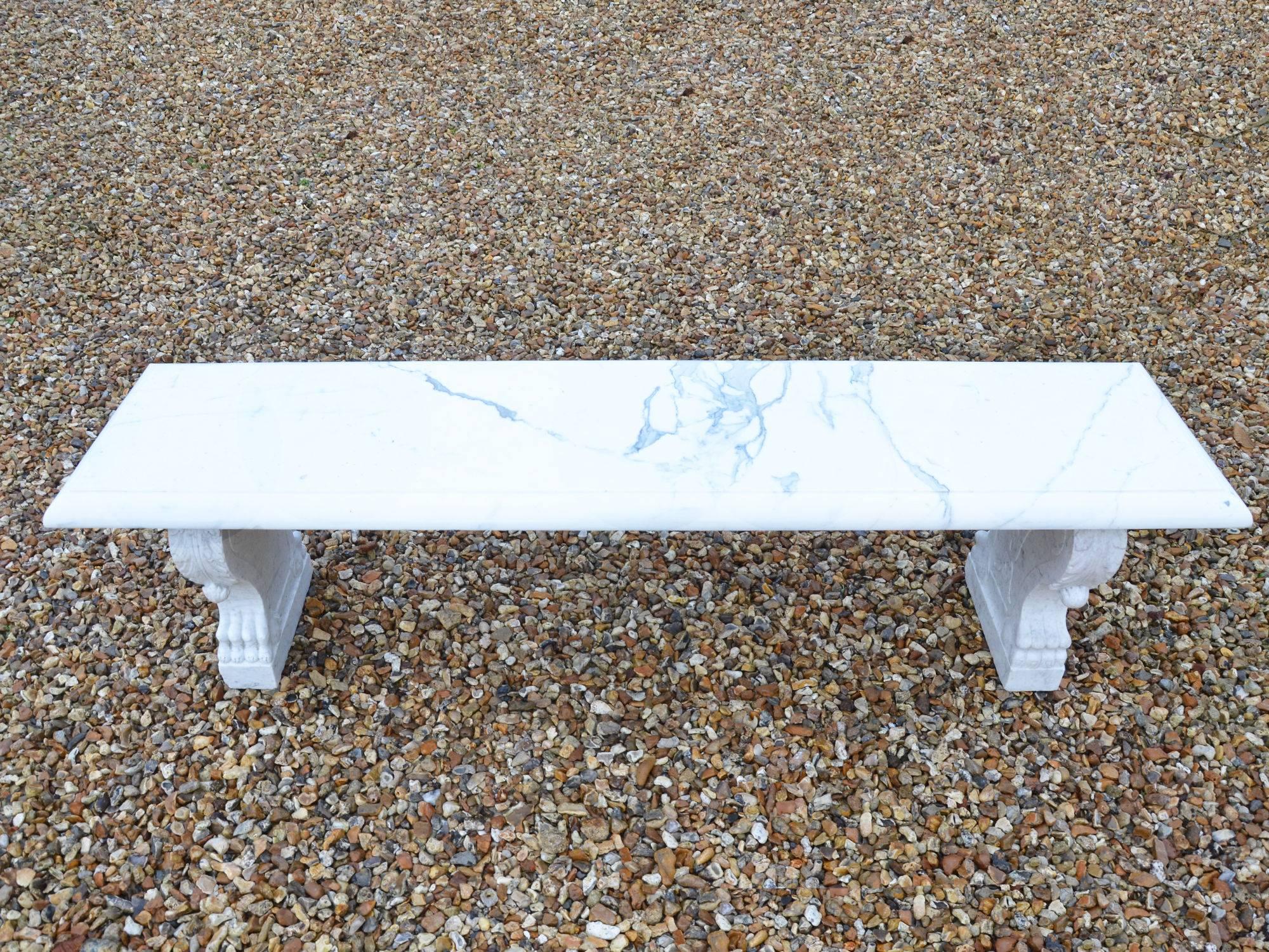 A white marble garden bench raised upon cabriole leg supports, having acanthus leaf decoration.