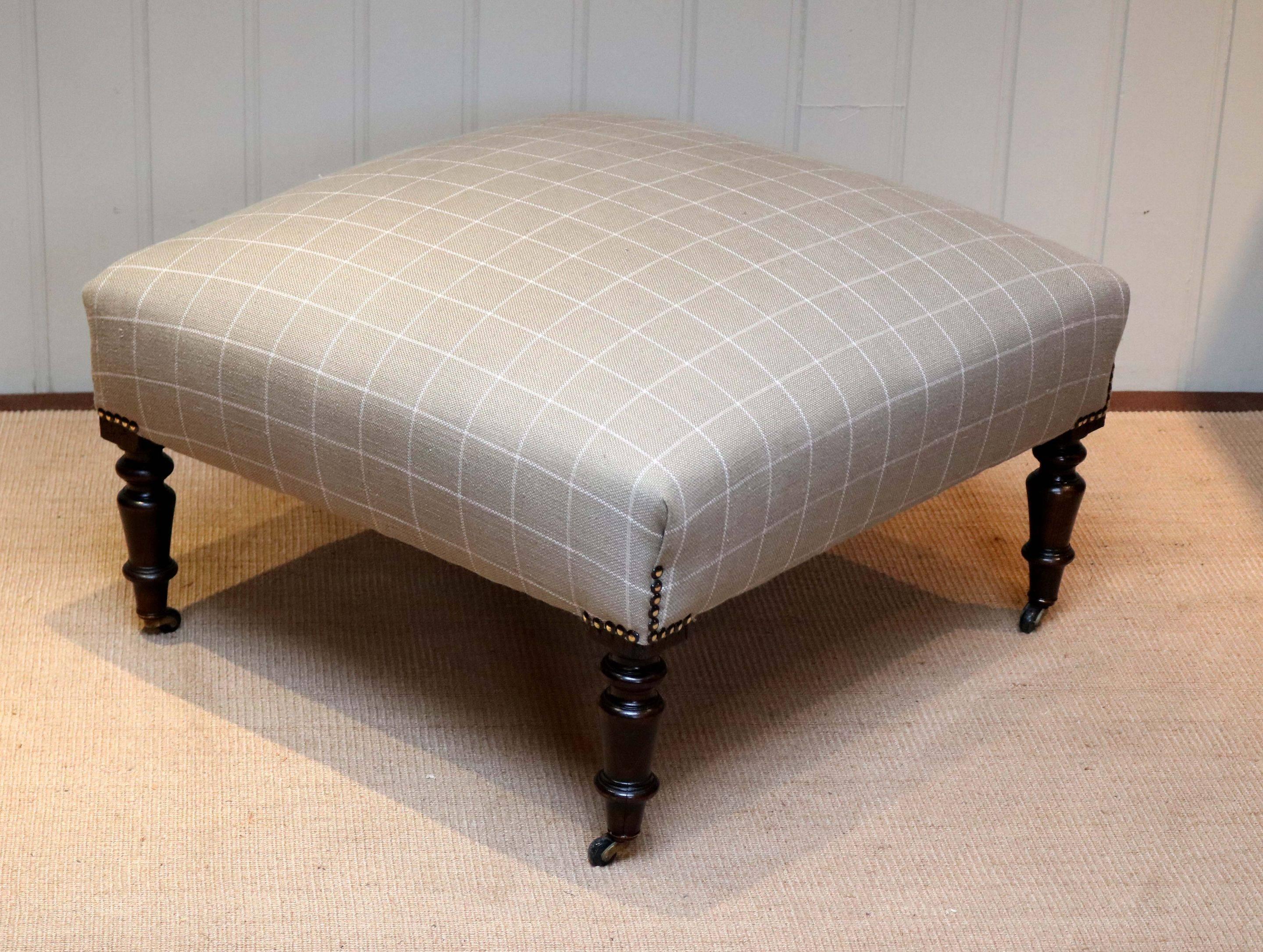 French beechwood framed upholstered footstool having turned wooden legs with original castors, reupholstered in a linen check fabric.
