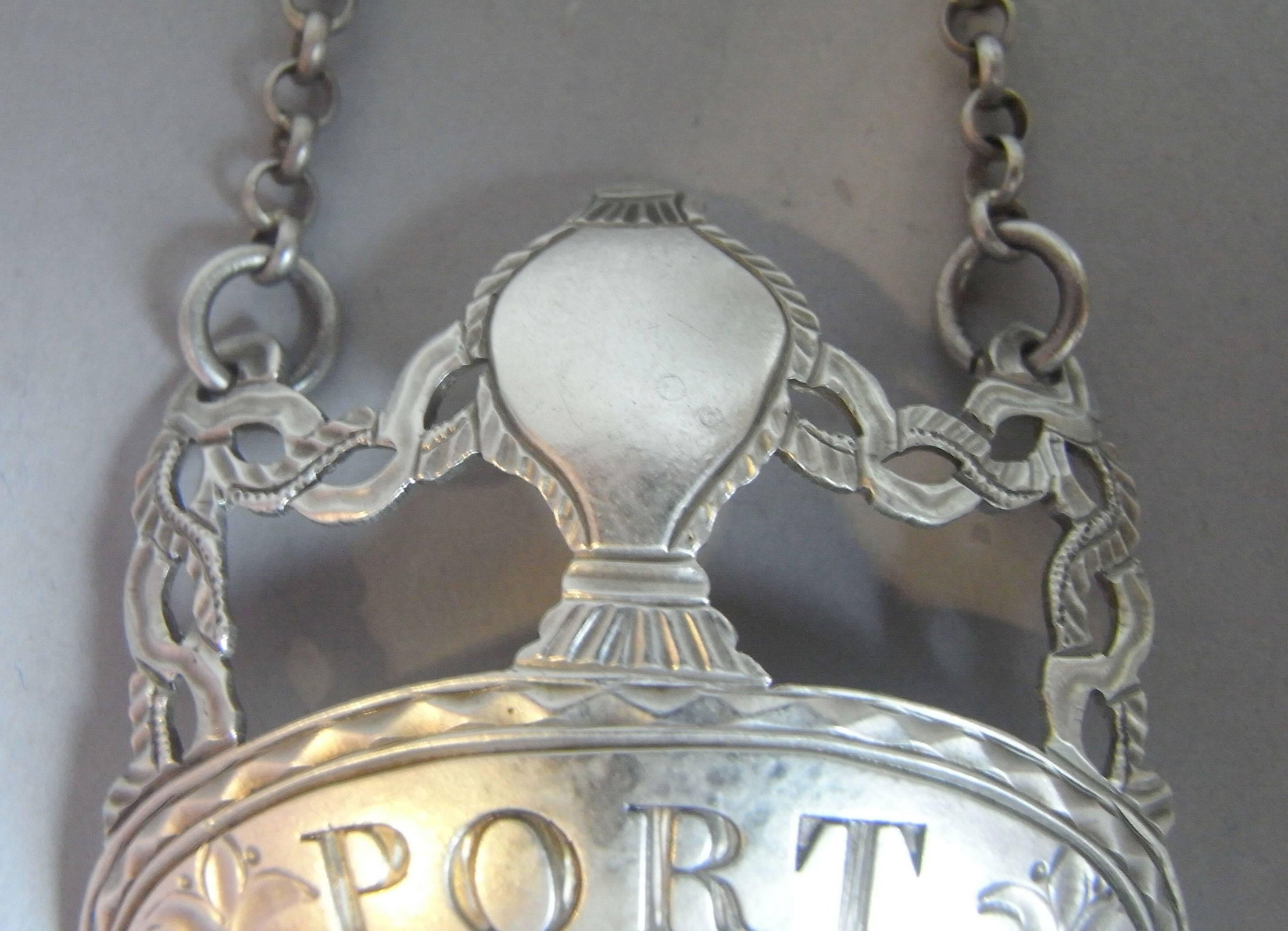 The label displays a crescent below which is engraved for PORT, with a reed and bright cut border. The face is also engraved with two floral sprigs. This scarce example displays the rare balloon shaped motif above flanked, on each side, by pierced