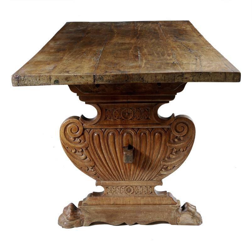 A wonderful Italian, Tuscan refectory table in Renaissance style. The rectangular top, constructed of three solid planks on carved cartouche trestle ends, decorated with scrolling leaves and rondels raised on paw feet, united by a shaped central