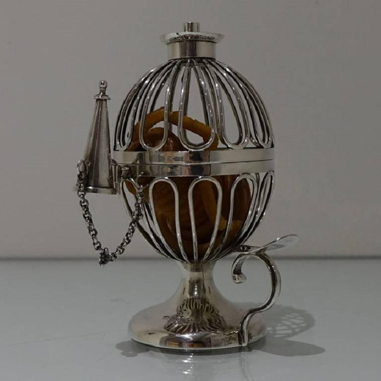 A very elegant wirework sphere shaped wax jack sitting on a raised circular pedestal foot which has reed decoration for lowlights. Attached to the foot is a stylish handle which is crowned with a shaped disc thumb piece.
