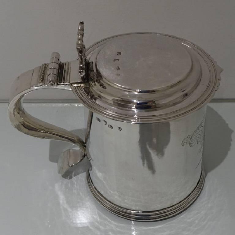 A stunningly beautiful large flat top tankard and cover with hinged lid. The tankard is plain formed in design with a cylindrical body which has a stylish hand engraved contemporary armorial to the centre front for importance. The lid has a