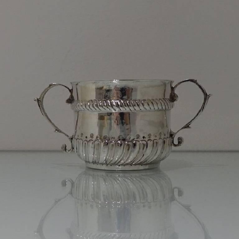 A rare and highly collectable William and Mary porringer with elegant swirl fluting for decoration to the lower section of the bowl and stylish scroll handles either side. The upper section has an elegant hand chased gadroon style gallery border for